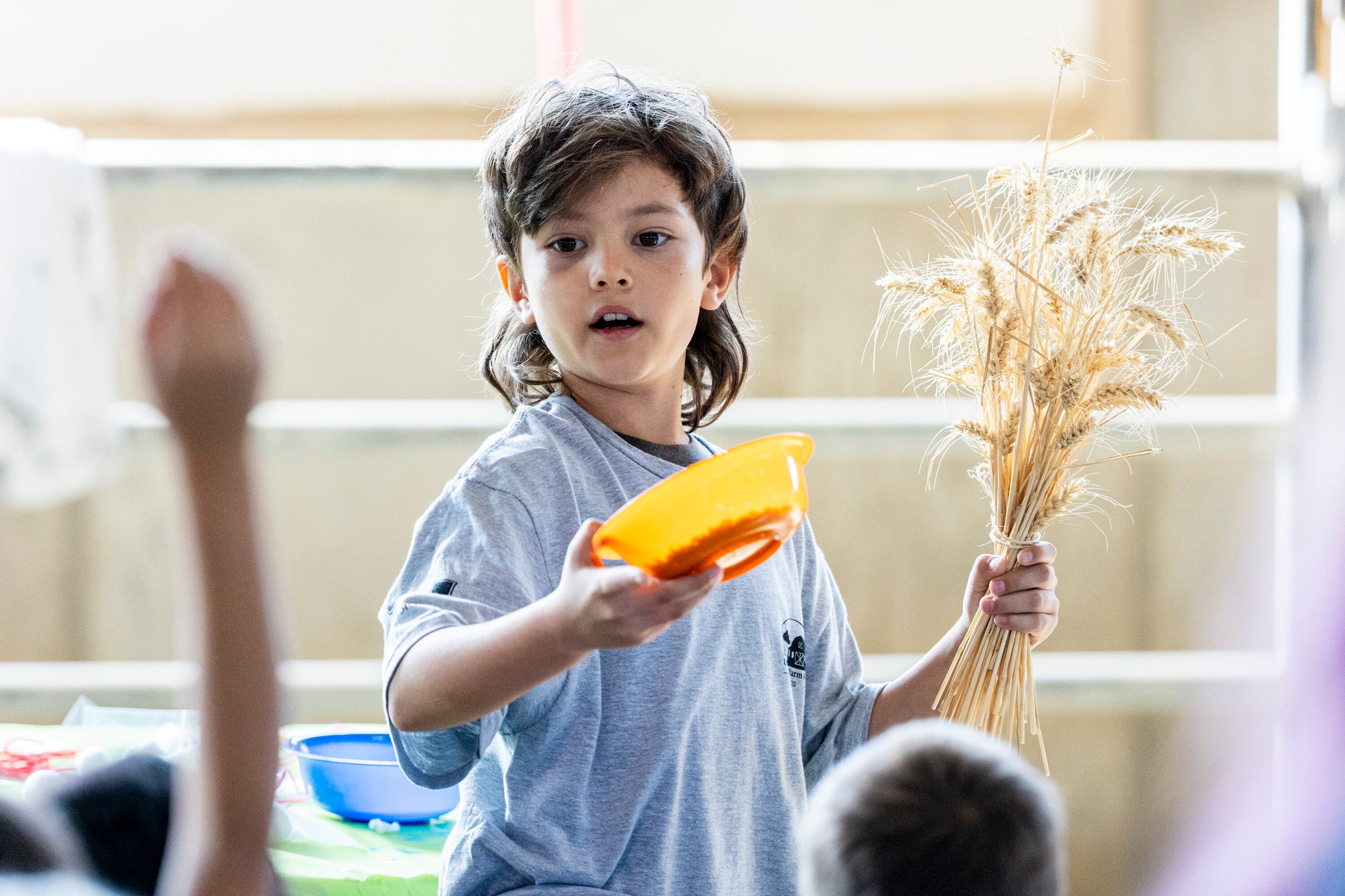 Cohen Hooper, a 4-H volunteer, points out a second grader to take their question as he holds wheat during Utah County Farm Field Days held by the Utah Farm Bureau and Utah State University Extension at the North Utah County Equestrian Park in Highland on Thursday.