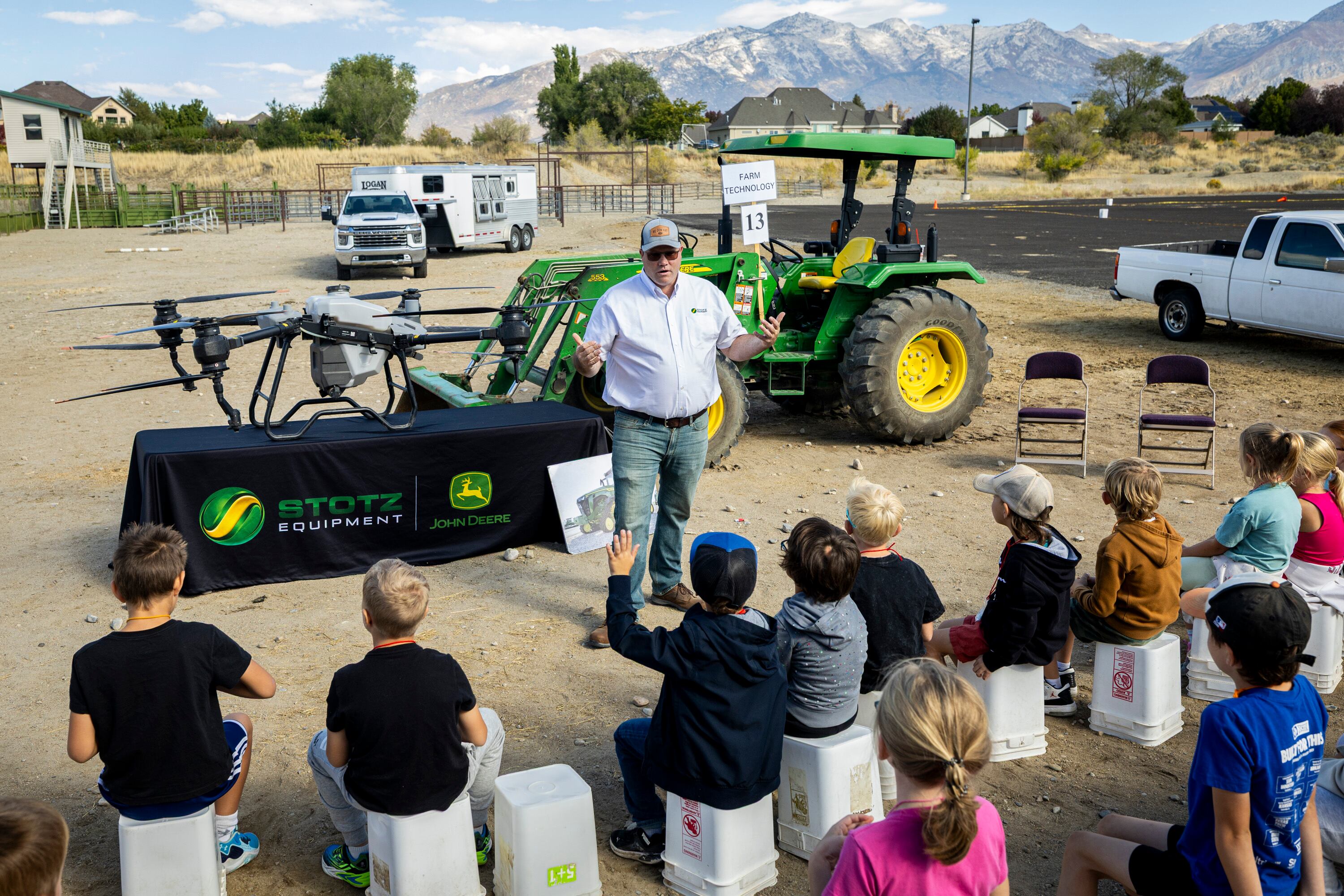 Dane Bateman, a service manager with Stotz Equipment, talks to second graders about farm equipment including an agricultural drone, left, and tractor, right, during Utah County Farm Field Days held by the Utah Farm Bureau and Utah State University Extension at the North Utah County Equestrian Park in Highland on Thursday.