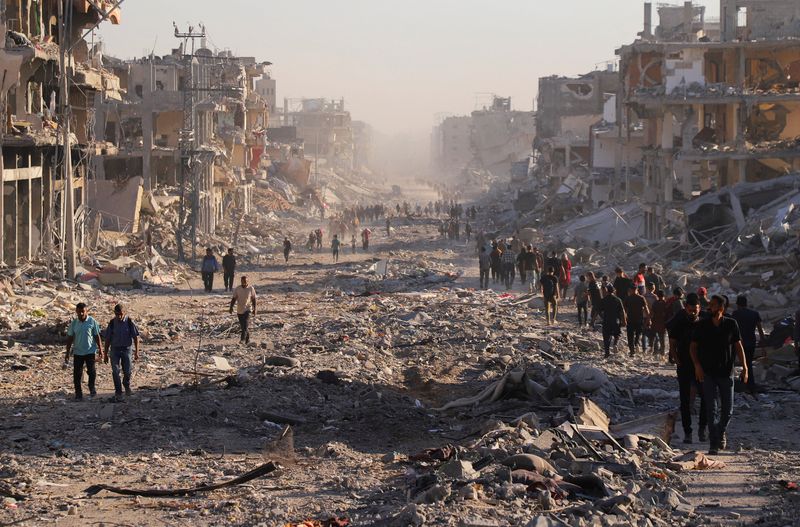 Palestinians walk through a damaged neighborhood in Gaza City, Friday. Many residents came home to rubble following the U.S.-brokered ceasefire that took effect.