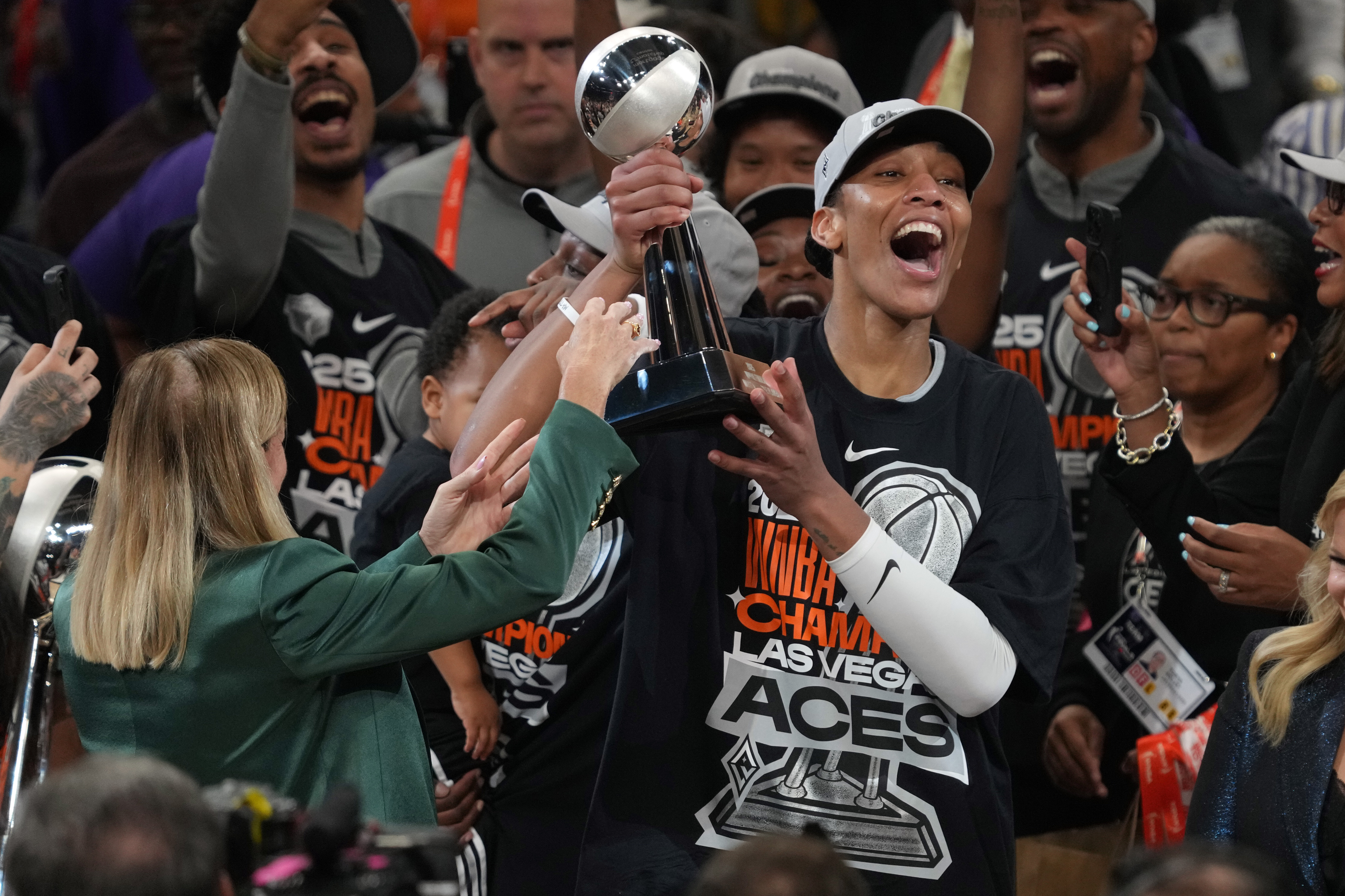 Las Vegas Aces center A'ja Wilson, center right, holds up her MVP trophy after Game 4 of the WNBA basketball finals against the Phoenix Mercury, Friday, Oct. 10, 2025, in Phoenix. 
