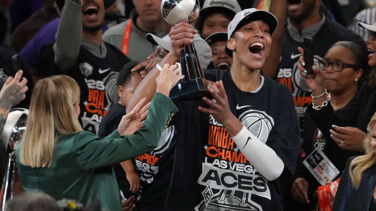 Las Vegas Aces center A'ja Wilson, center right, holds up her MVP trophy after Game 4 of the WNBA basketball finals against the Phoenix Mercury, Friday, Oct. 10, 2025, in Phoenix.
