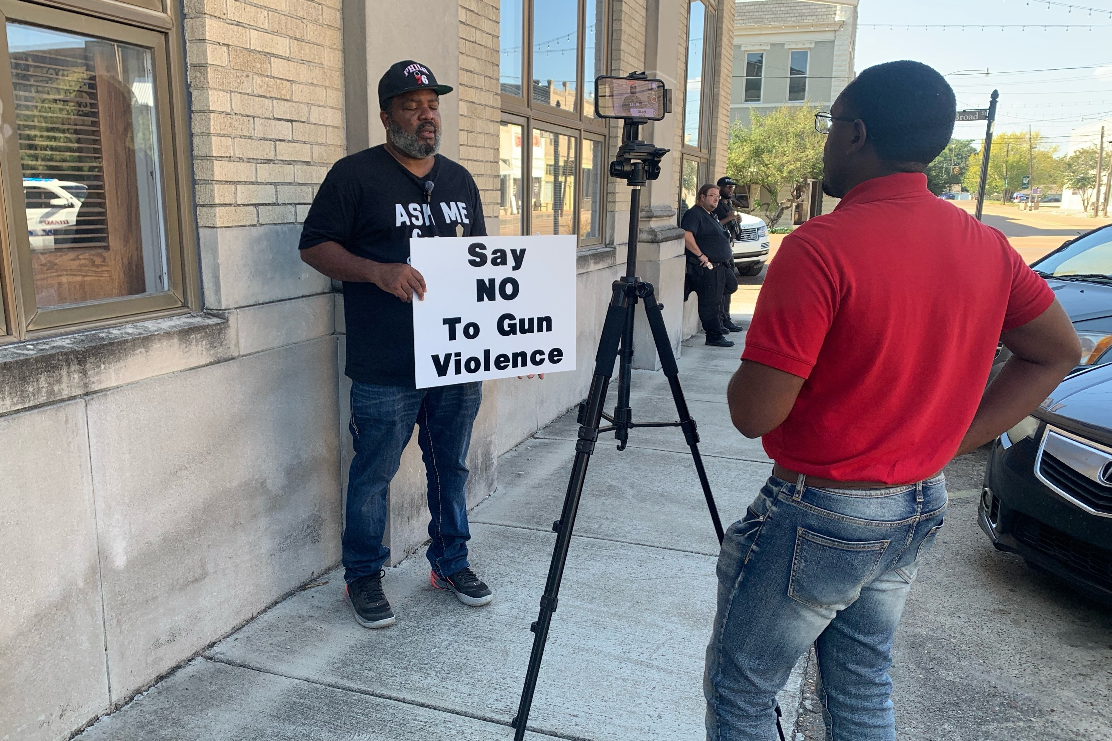 A man holds a sign as he is interviewed after a deadly shooting Friday night in downtown Leland, Miss.,on Saturday. Eight people were killed in separate shootings after high school homecoming celebrations in the area.