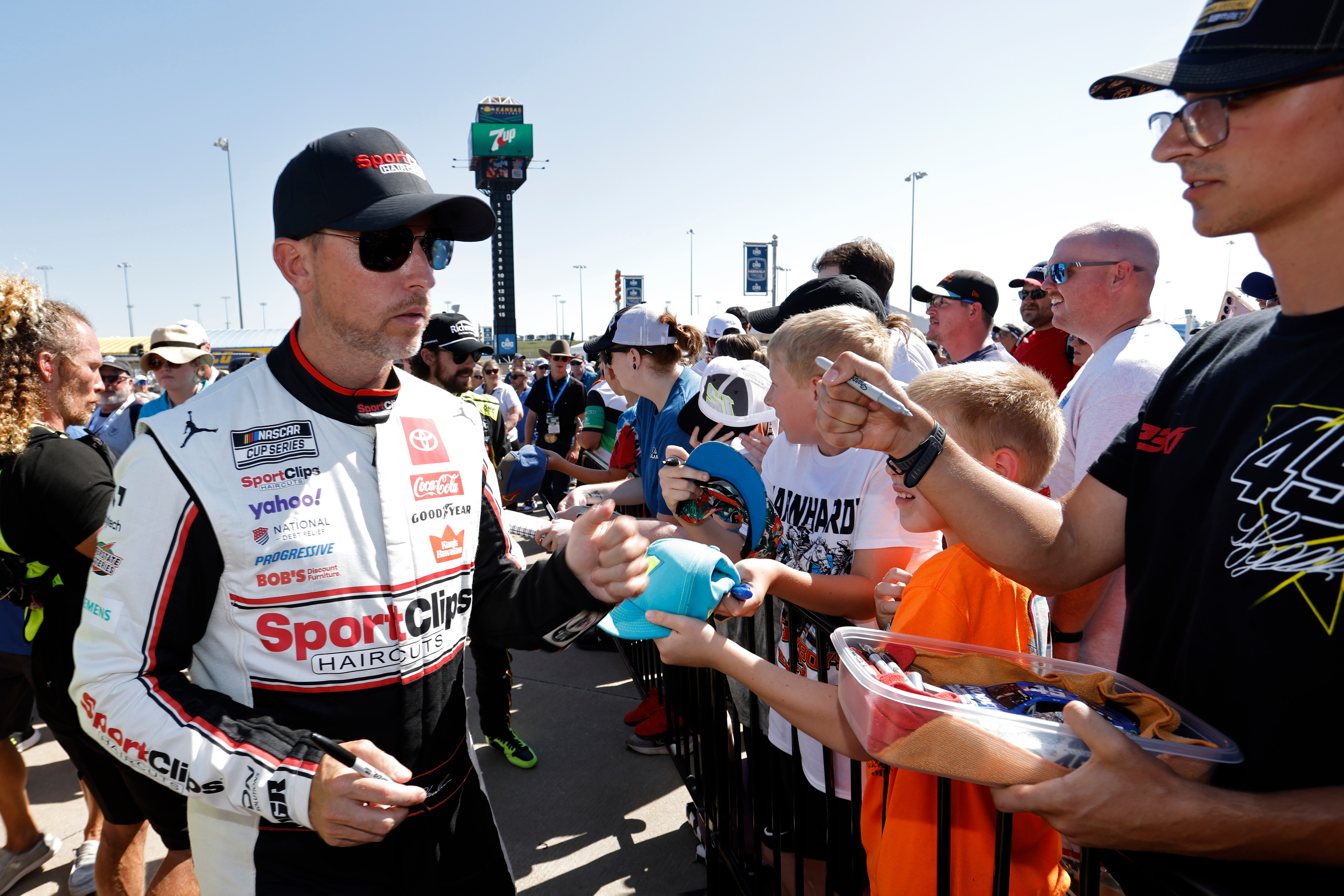 Denny Hamlin, left, gives autographs before a NASCAR Cup Series auto race at Kansas Speedway in Kansas City, Kan., Sunday, Sept. 28, 2025.