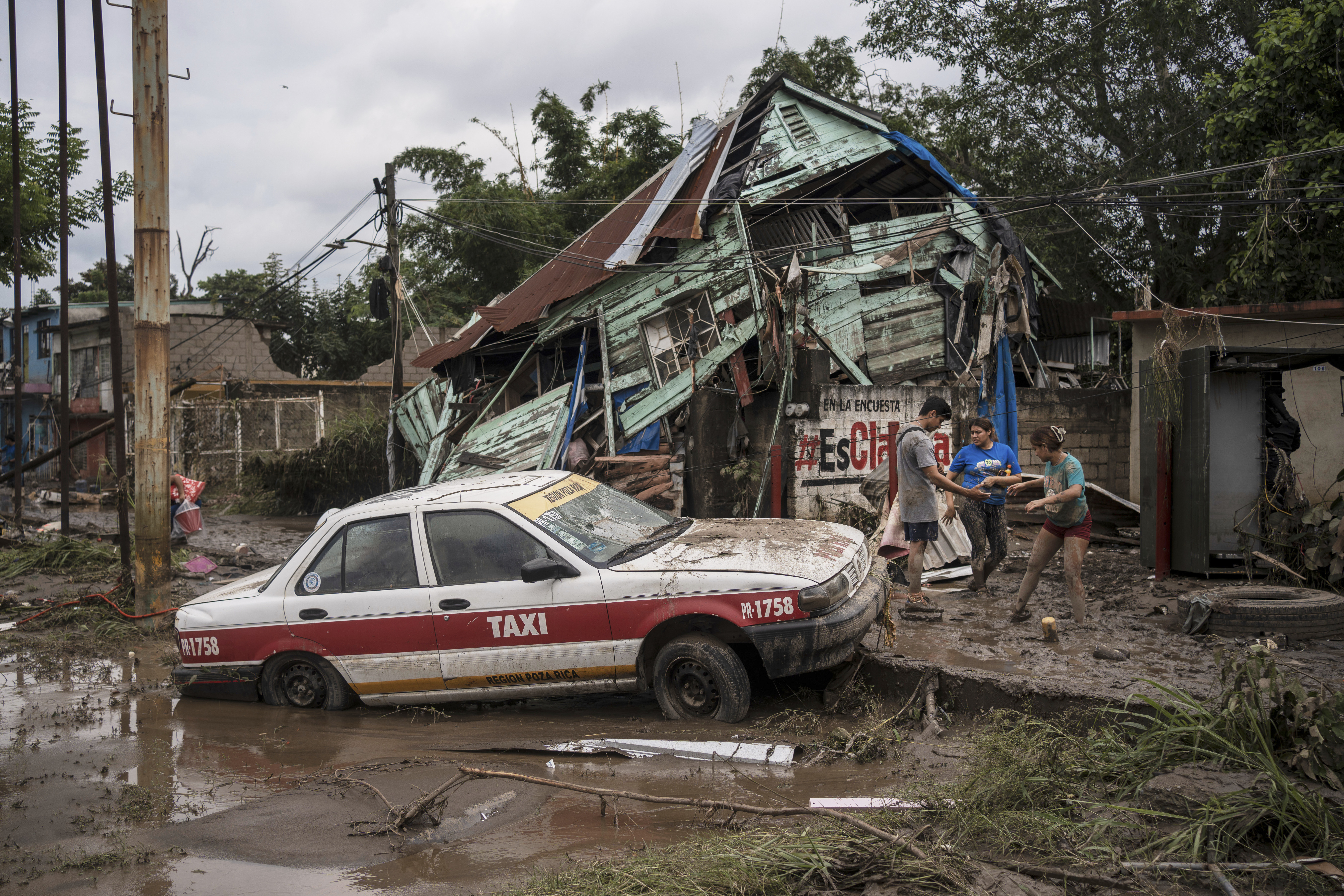 Neighbors gather around a damaged house after heavy rainfall in Poza Rica, Veracruz state, Mexico, Saturday.