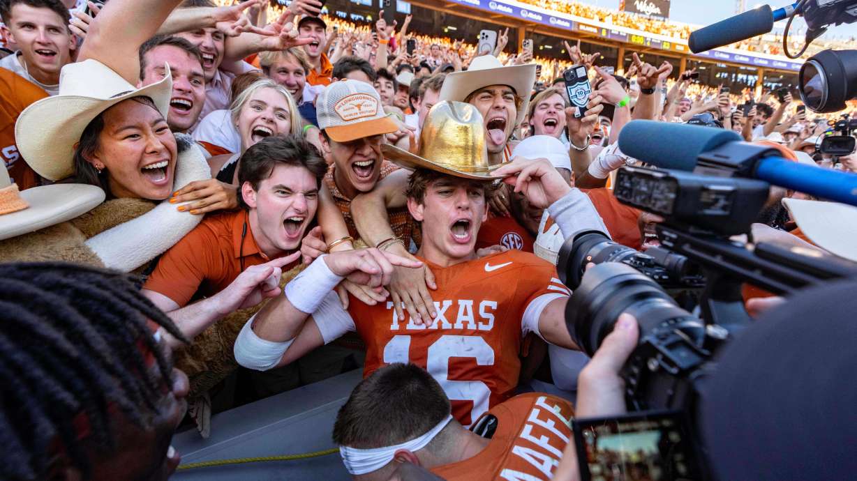 Texas quarterback Arch Manning, center, celebrates with fans after defeating Oklahoma in an NCAA college football game Saturday, Oct. 11, 2025, in Dallas.