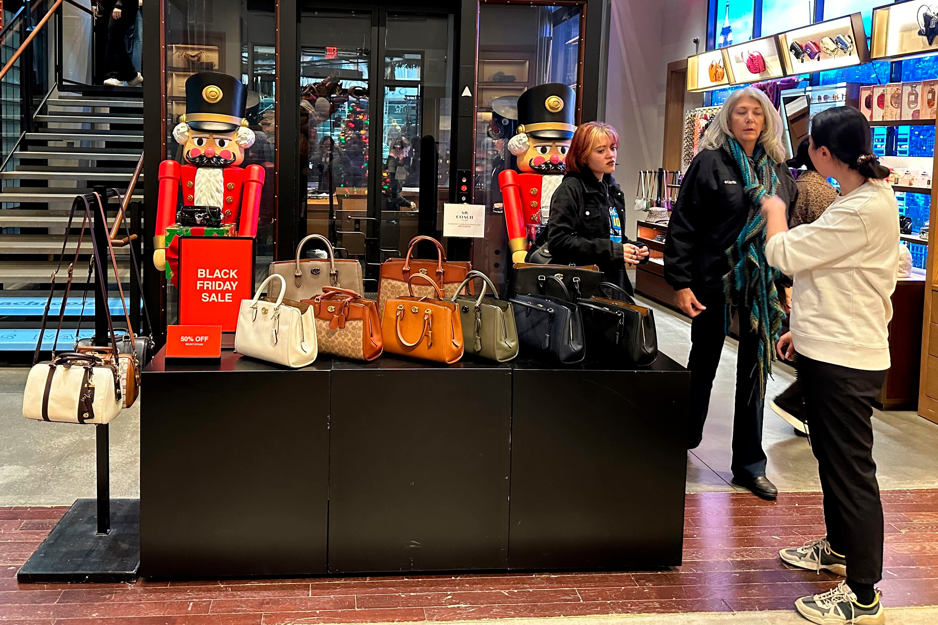 Shoppers pause near a display of handbags at a Coach store in New York on Nov. 19, 2023.