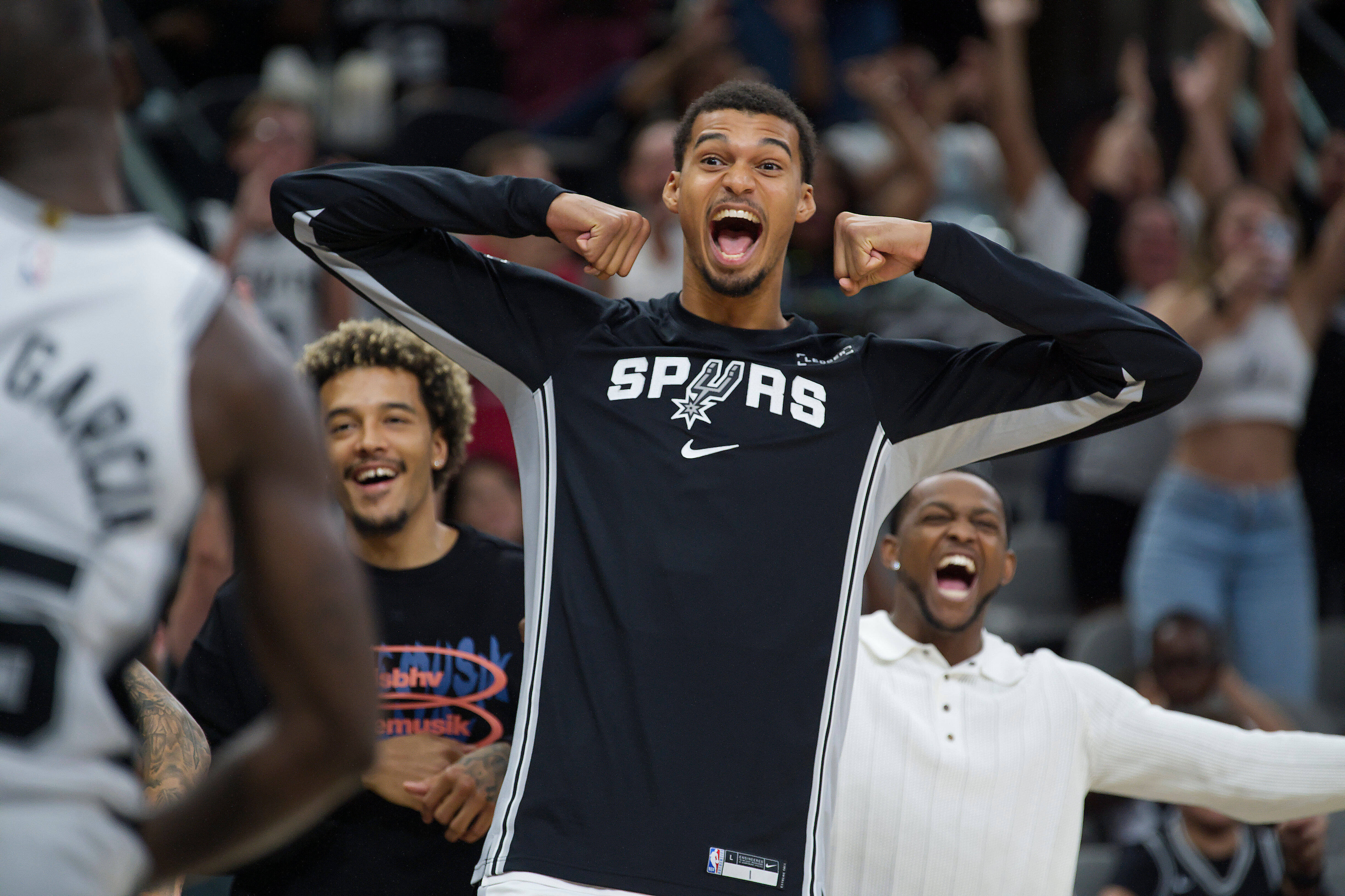 San Antonio Spurs center Victor Wembanyama, center, celebrates after a basket by Spurs guard David Jones Garcia, left, in overtime during a preseason NBA basketball game against the Utah Jazz, Friday, Oct. 10, 2025, in San Antonio.