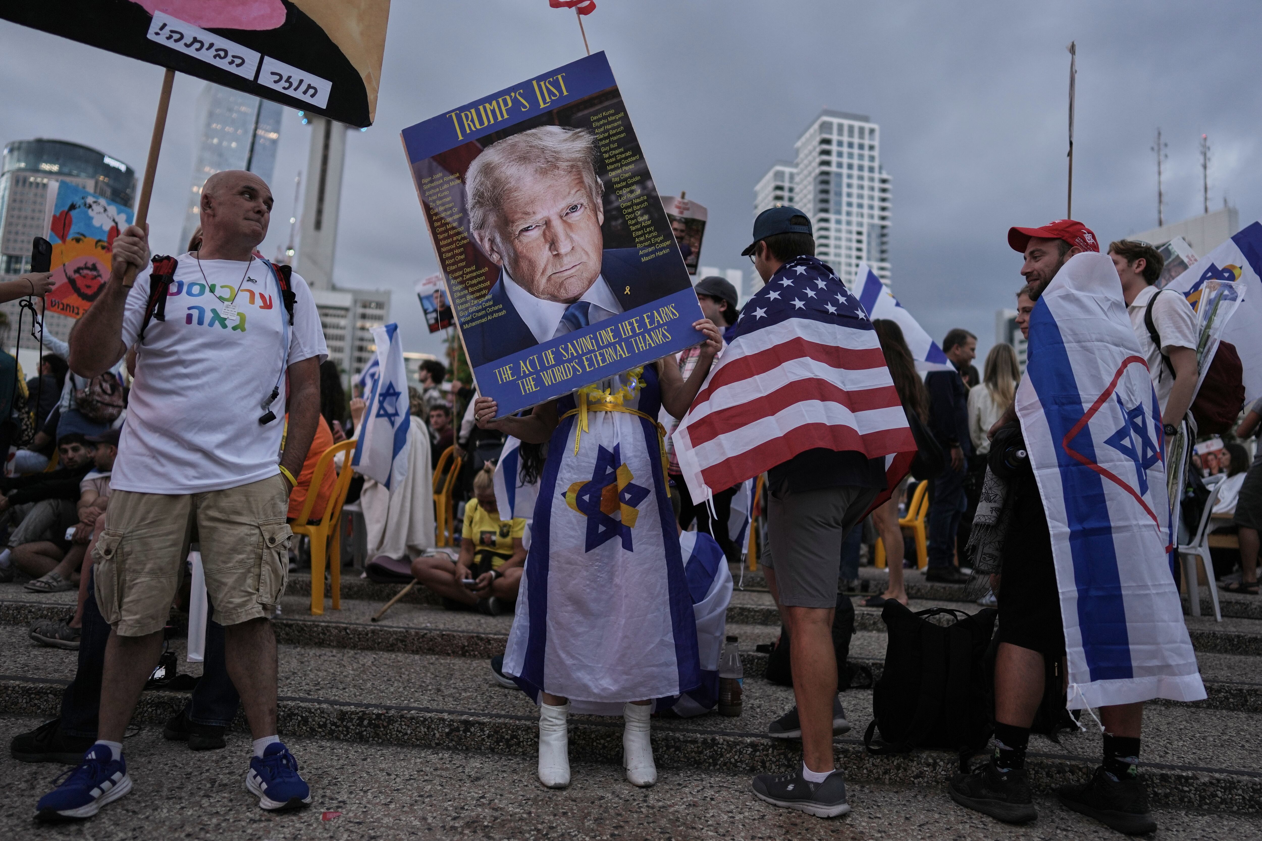 A woman holds an image of President Donald Trump during a gathering at a plaza known as hostages square in Tel Aviv, Israel, Monday, before the release of Israeli hostages held in Gaza.
