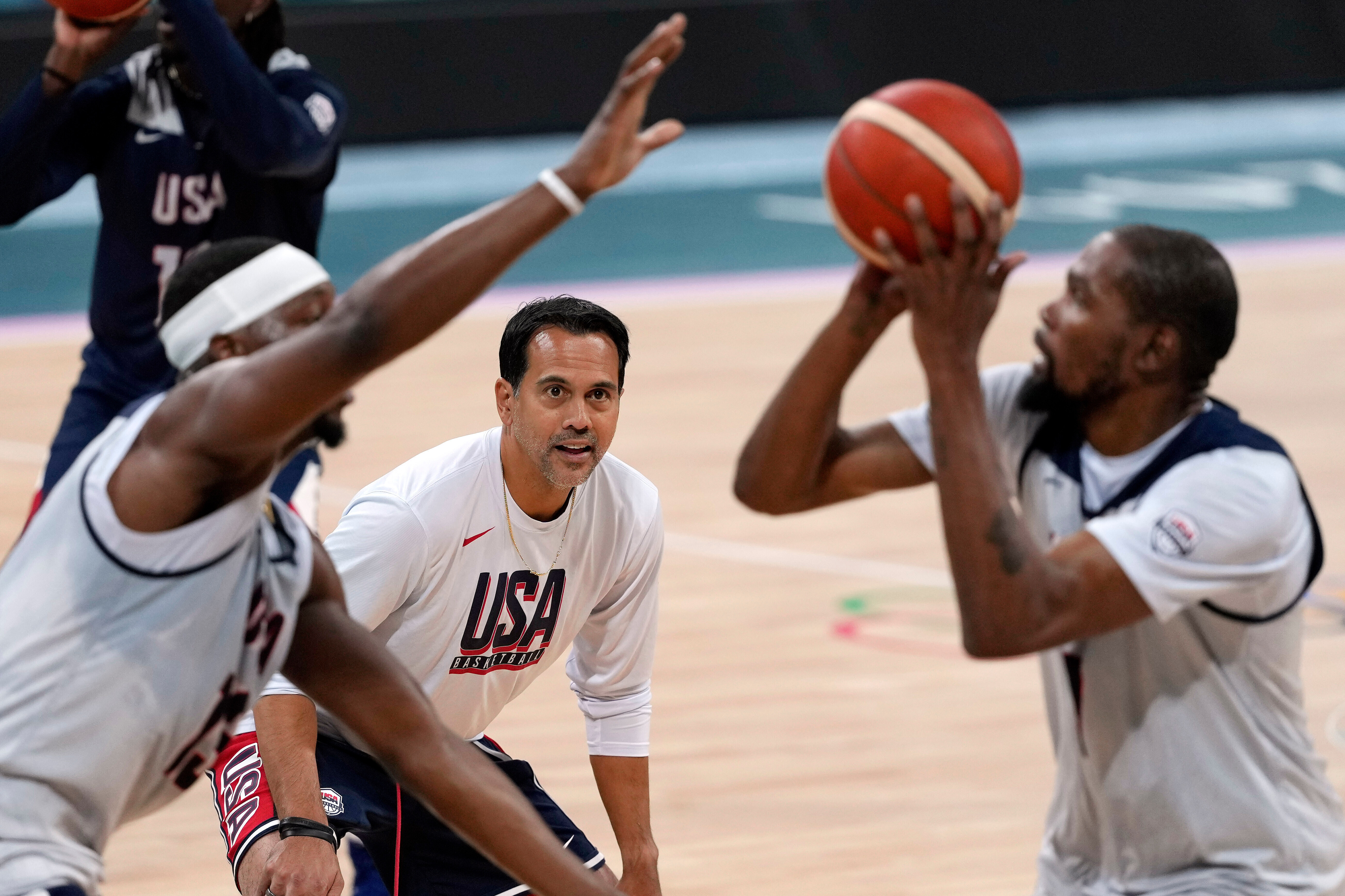 FILE - United State's Kevin Durant, right, shoots as Bam Adebayo, left, defends while assistant coach Erik Spoelstra watches during men's basketball practice at the 2024 Summer Olympics, Wednesday, July 24, 2024, in Villeneuve-d'Ascq, France.