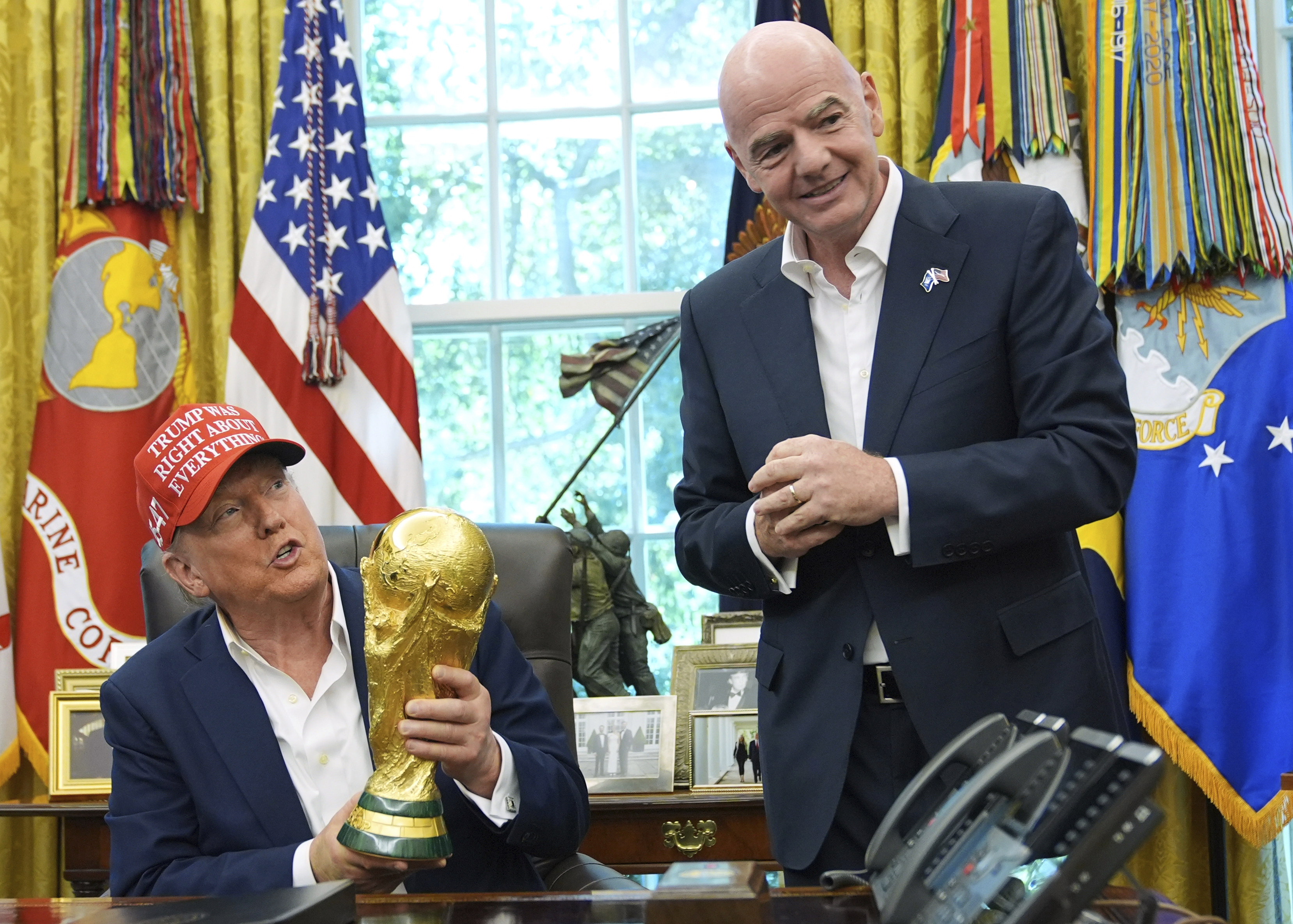 FILE - President Donald Trump holds the FIFA World Cup Winners Trophy as FIFA President Gianni Infantino looks on during an announcement in the Oval Office of the White House, Aug. 22, 2025, in Washington.