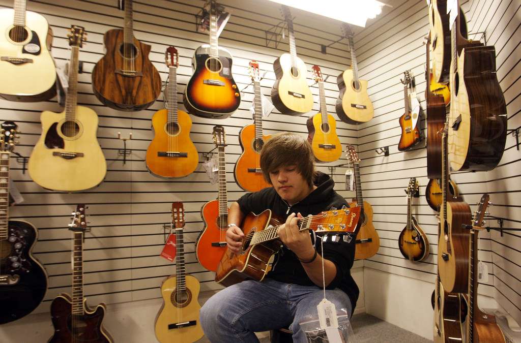 Jacob Brown tries out a guitar at Guitar Czar in Millcreek Township, Friday, Oct. 12, 2012. The store has announced its closure for next weekend due to tariffs and a slow economy.