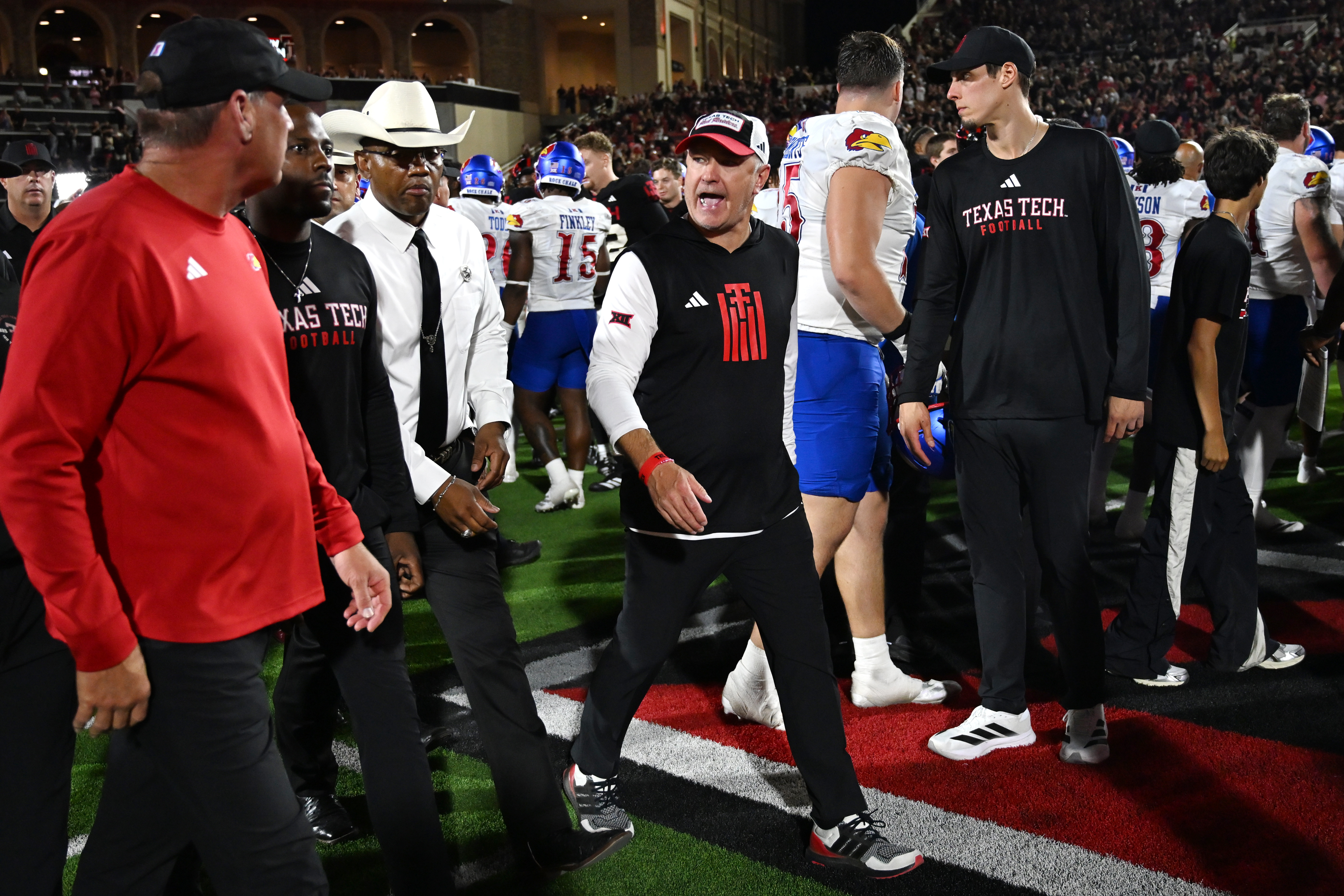 Texas Tech head coach Joey McGuire, center, speaks to Kansas head coach Lance Leipold, left, after the end of the NCAA college football game, Saturday, Oct. 11, 2025, in Lubbock, Texas.
