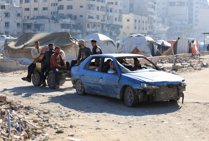 Palestinians in a car pull a cart with people on it, while driving near tents, amid a ceasefire between Israel and Hamas, in Gaza City, Wednesday. A resident called the situation "utterly tragic."