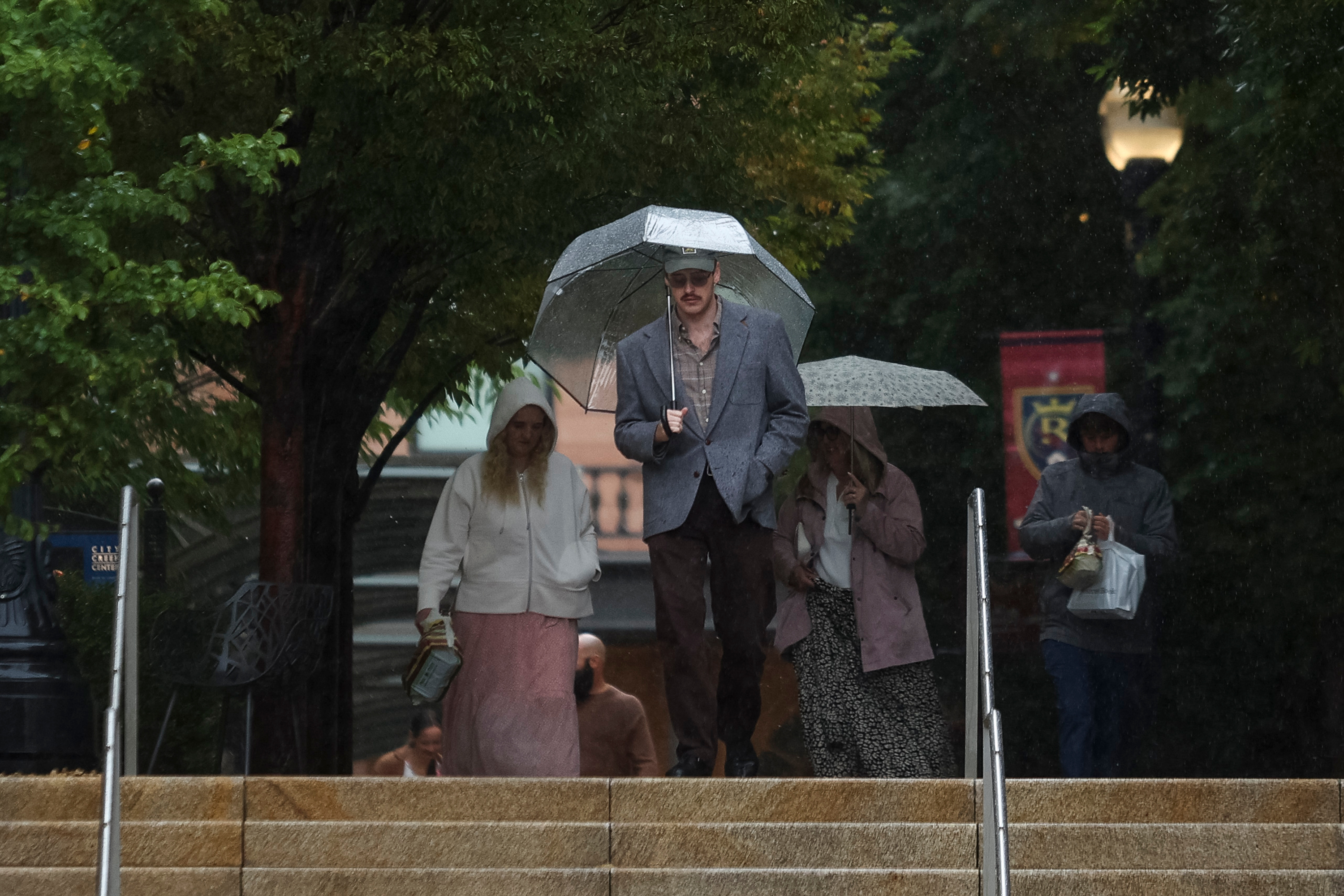 People shelter under umbrellas as they walk down a set of stairs near the City Creek Center in Salt Lake City on Oct. 4. This month's storms continue to improve Utah's drought situation, but the state has a long way to go.