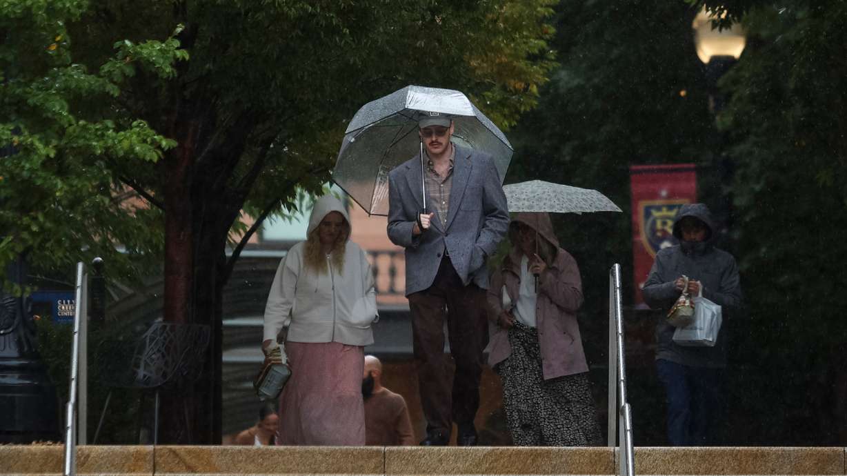 People shelter under umbrellas as they walk down a set of stairs near the City Creek Center in Salt Lake City on Oct. 4. After a dry start to November, valley rain and mountain snow return to the state's forecast this weekend.