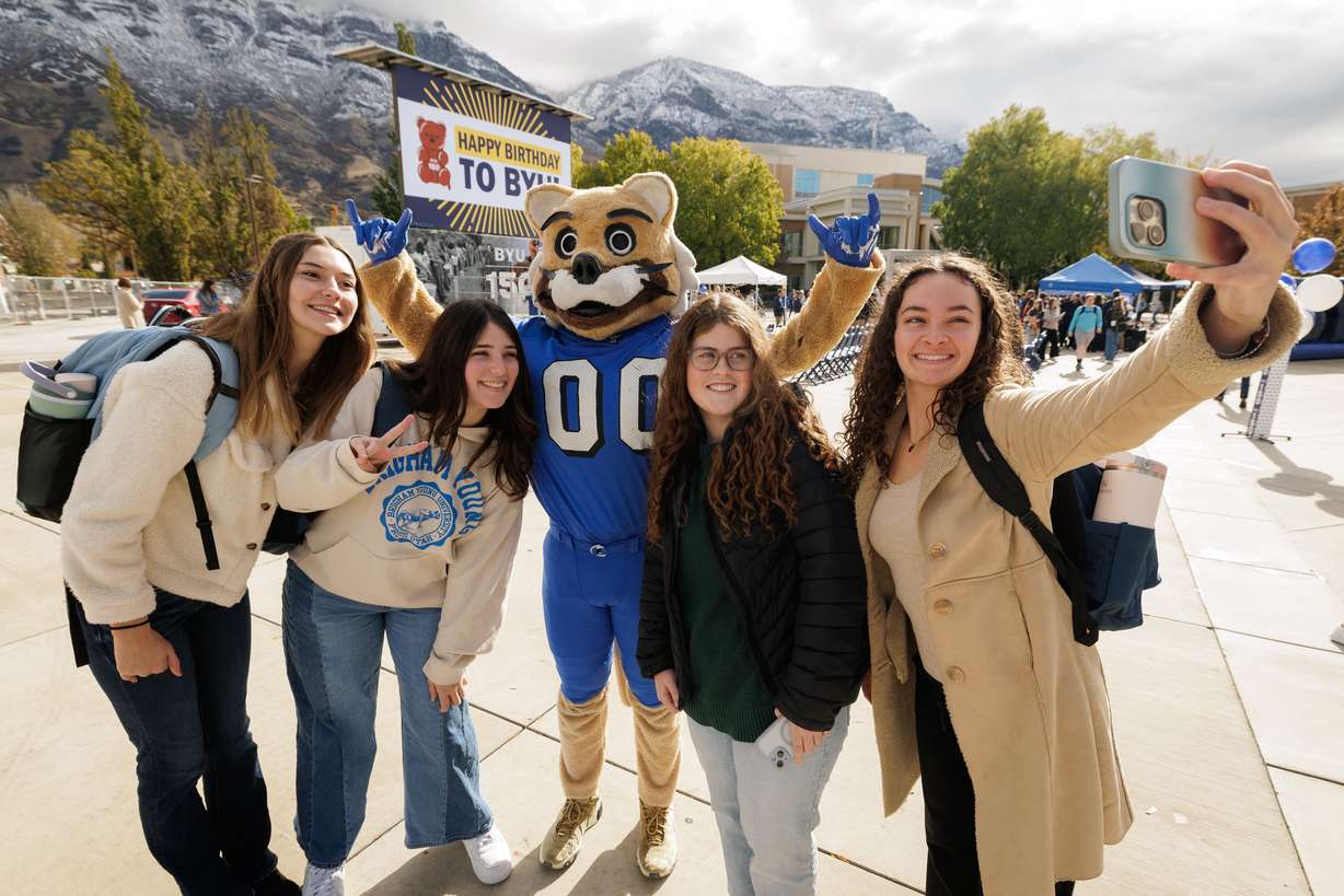 Students pose with a period-accurate Cosmo the Cougar in Provo on Thursday, where a time capsule in the cornerstone of the Harold B. Lee Library was unveiled.