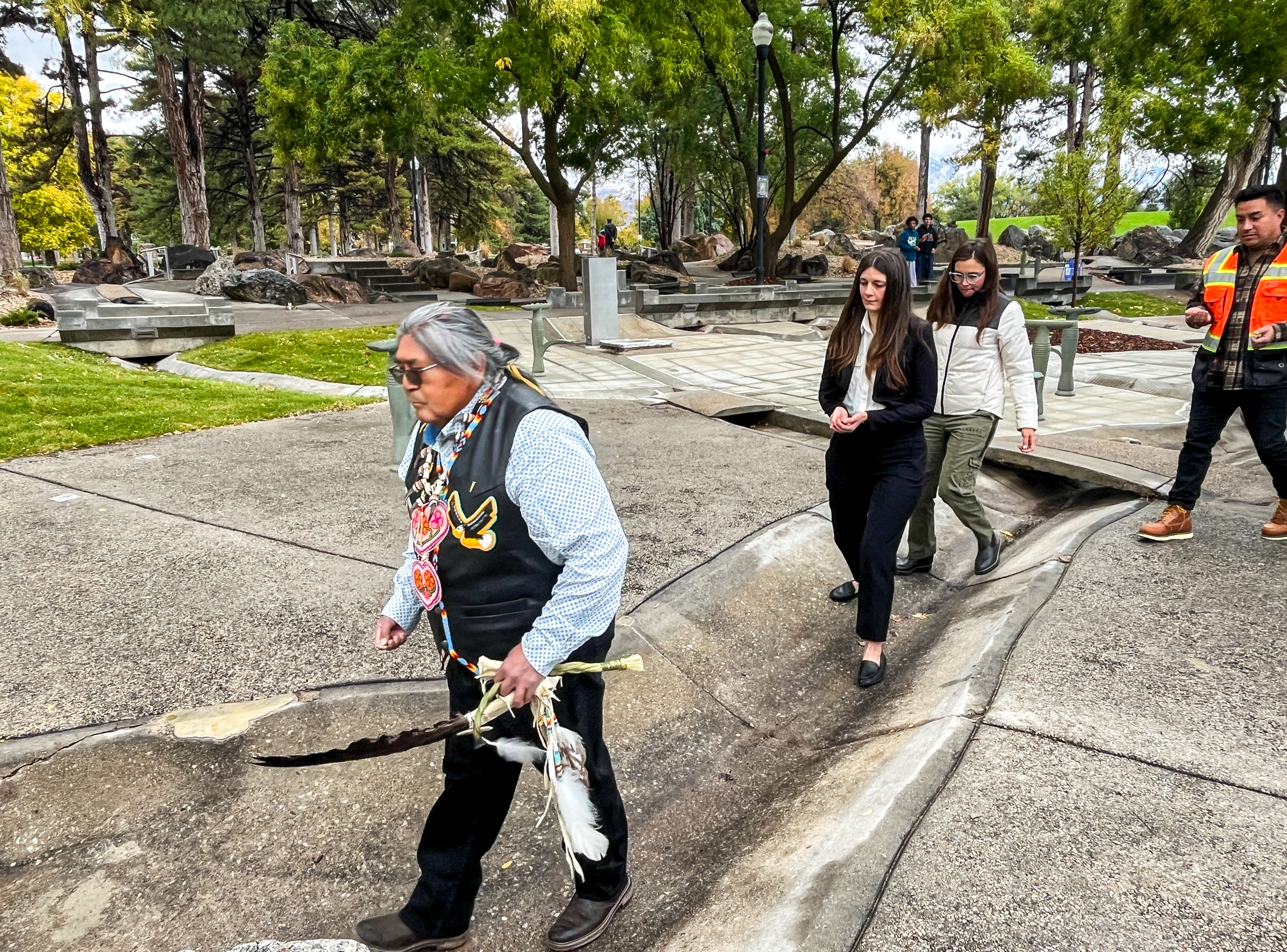 Rios Pacheco, a member of Utah's Northwestern Band of Shoshone, leads Felicia Baca, director of the Salt Lake City Arts Council, Salt Lake City Mayor Erin Mendenhall and others in a ceremony for the Seven Canyon Refuge at Liberty Park in Salt Lake City Thursday.