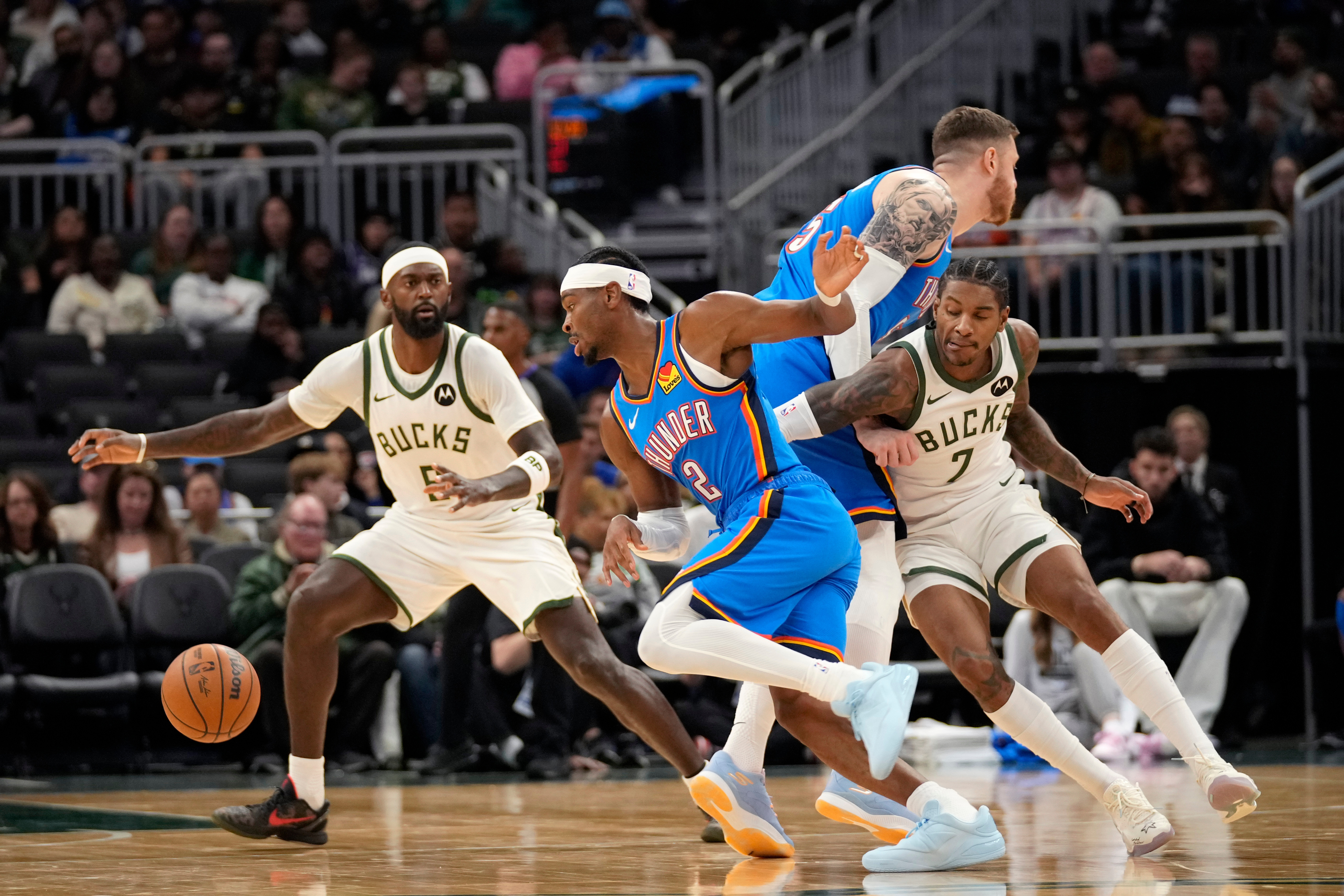 Milwaukee Bucks guard/forward Kevin Porter Jr. (7) attempts to get around Oklahoma City Thunder center Isaiah Hartenstein, second from right, as he trails behind Oklahoma City Thunder guard Shai Gilgeous-Alexander (2) as Milwaukee Bucks forward Bobby Portis (9) looks on during the first half of a preseason NBA basketball game Tuesday, Oct. 14, 2025, in Milwaukee.