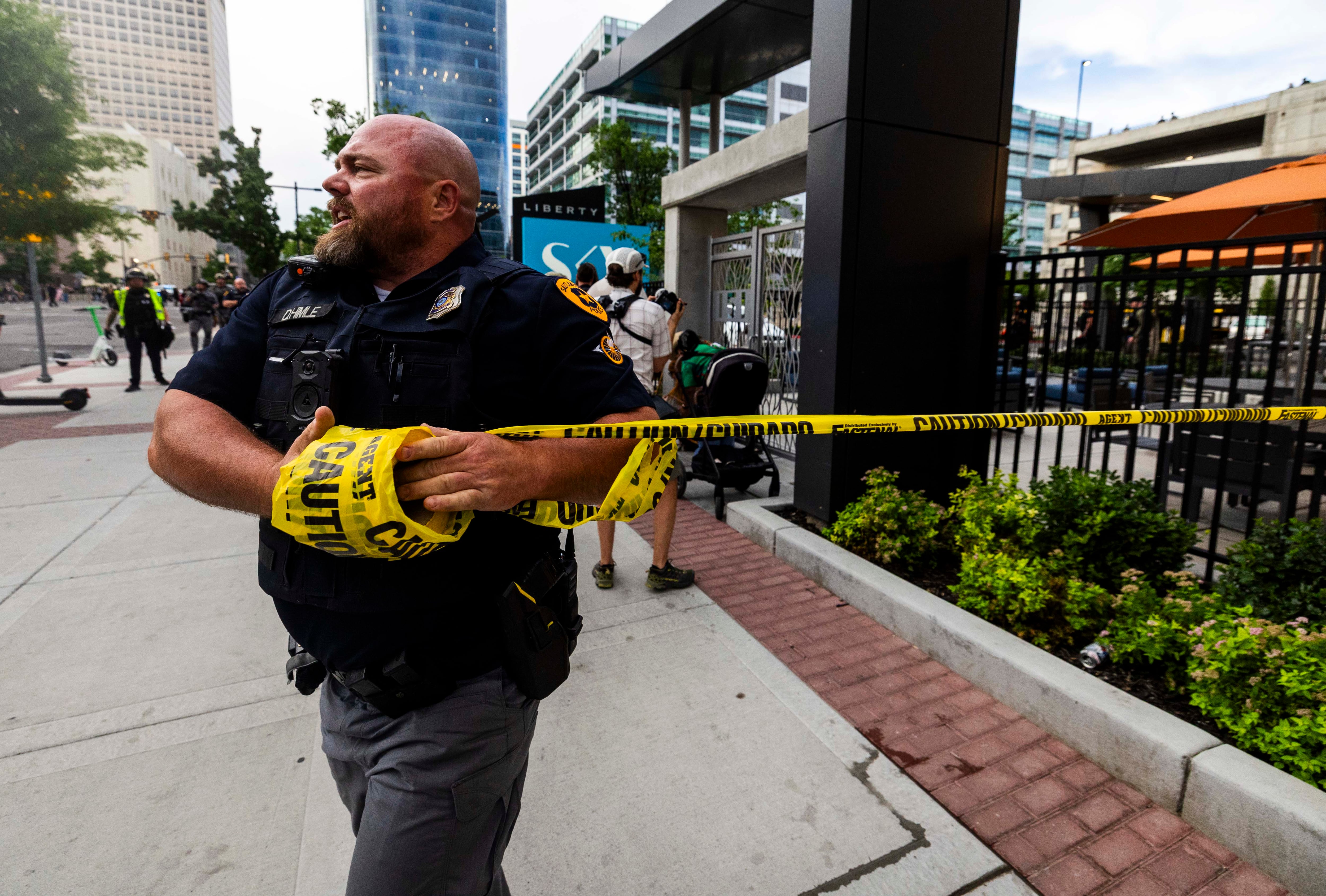 A police officer puts up crime scene tape after a reported shooting during a “No Kings” protest and march in Salt Lake City on June 14.