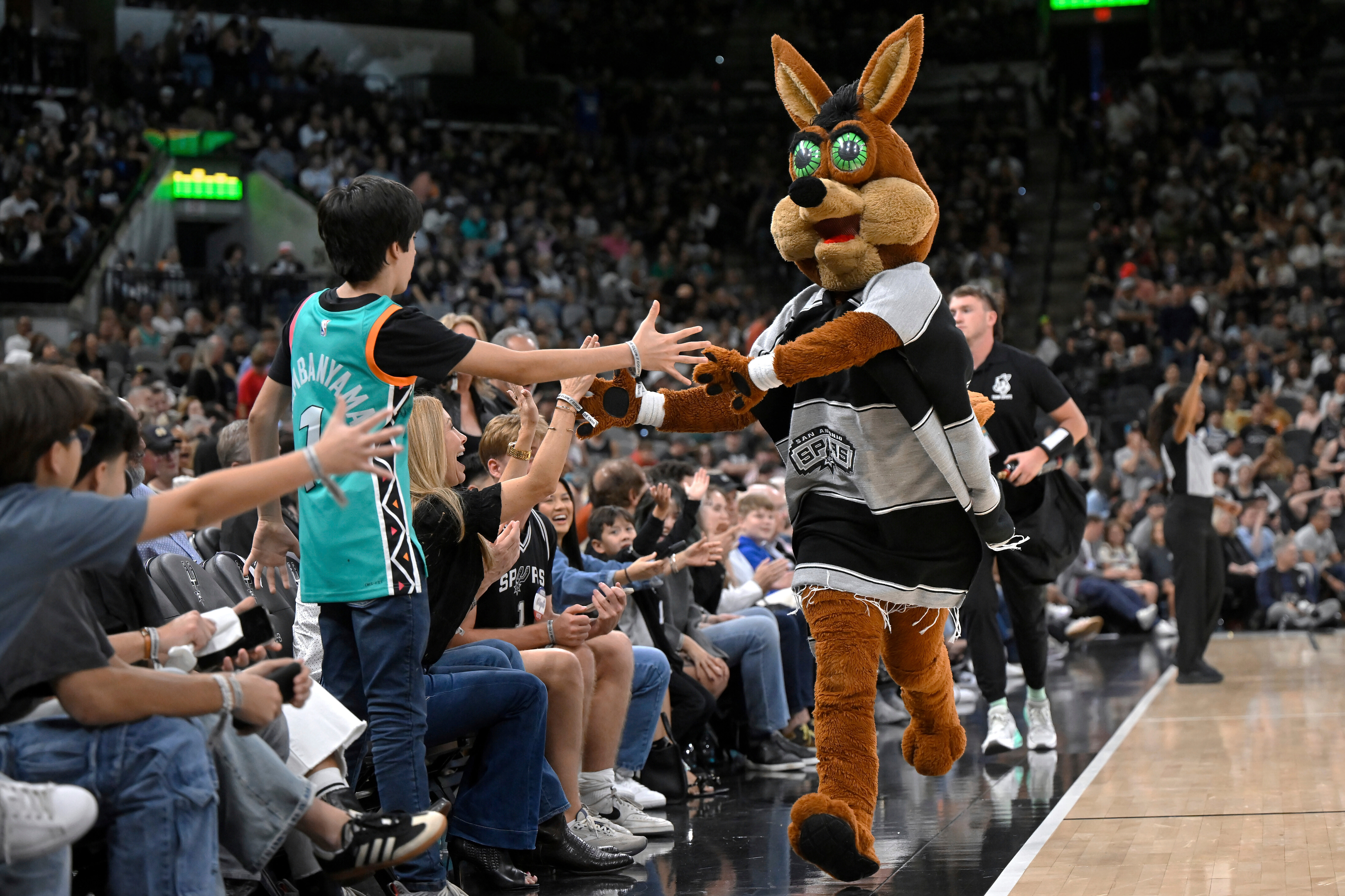 FILE - The Coyote, right, San Antonio Spurs' mascot, greets fans during the second half of an NBA basketball game against the Minnesota Timberwolves, Saturday, Nov. 2, 2024, in San Antonio. San Antonio won 113-103. 
