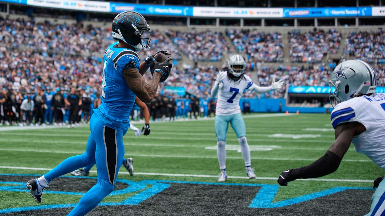 Carolina Panthers wide receiver Tetairoa McMillan (4) catches a touchdown pass in front of Dallas Cowboys' Trevon Diggs (7) and Donovan Wilson, right, in the second half of an NFL football game, Sunday, Oct. 12, 2025, in Charlotte, N.C.