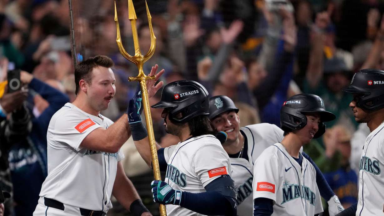 Seattle Mariners' Eugenio Suárez holds the trident after hitting a grand slam home run during the eighth inning in Game 5 of baseball's American League Championship Series against the Toronto Blue Jays, Friday, Oct. 17, 2025, in Seattle.