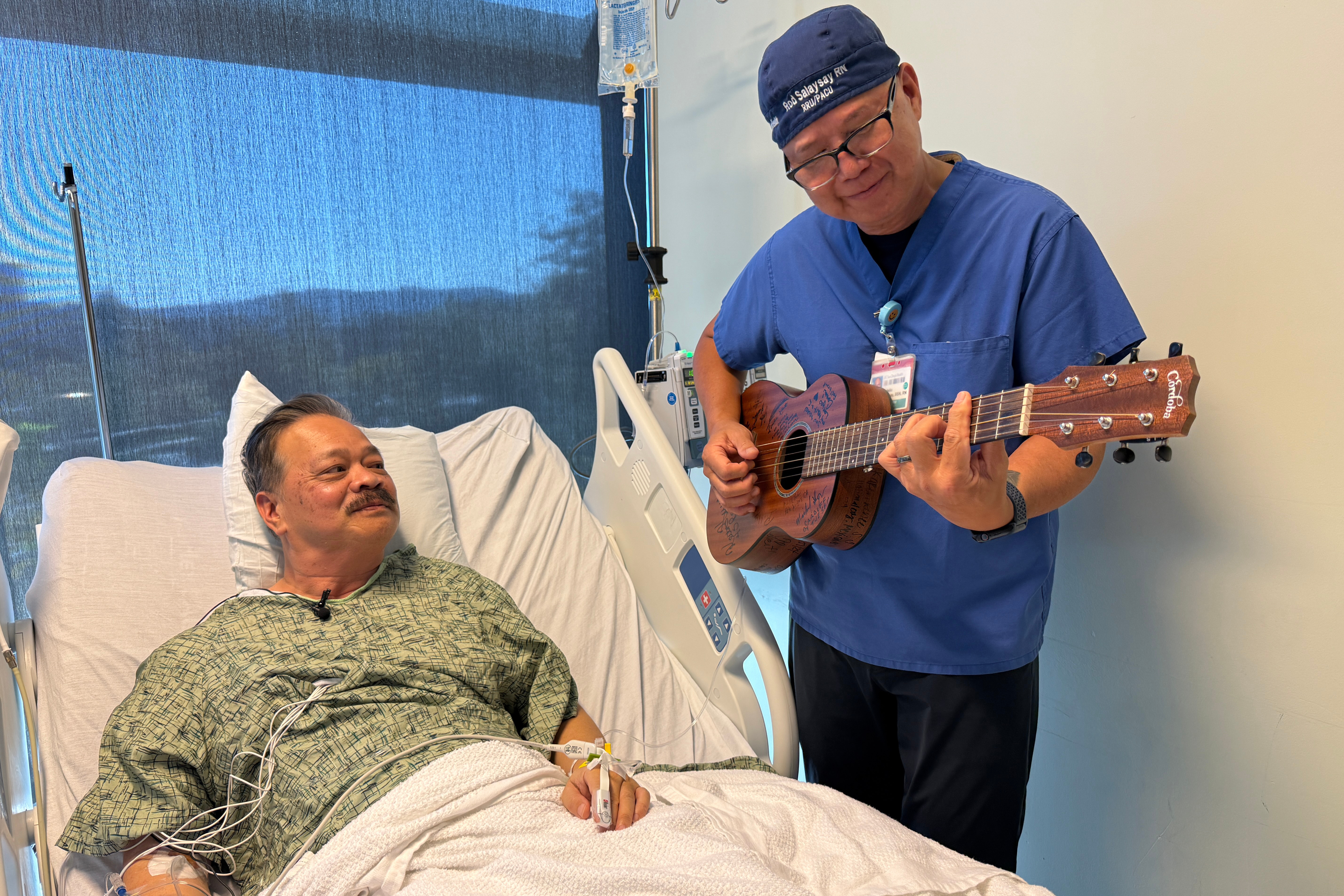 Nurse Rod Salaysay plays guitar for patient Richard Hoang in the recovery unit of UC San Diego Health in San Diego on Sept. 30.