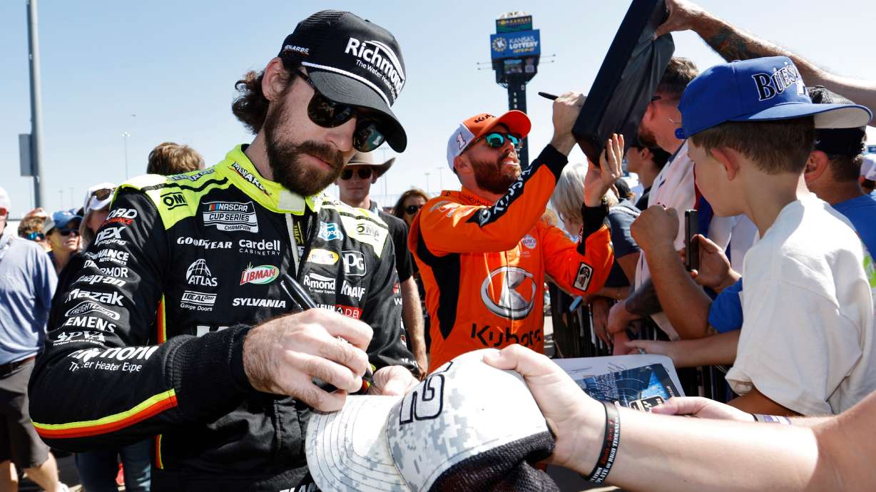 CORRECTS TO ROSS CHASTAIN NOT BUBBA WALLACE - Ryan Blaney, left, and Ross Chastain, center, give autographs before a NASCAR Cup Series auto race at Kansas Speedway in Kansas City, Kan., Sunday, Sept. 28, 2025.