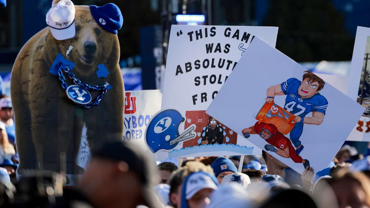Fans hold up signs during Fox’s “Big Noon Kickoff” show at Brigham Young University in Provo on Saturday, Oct. 18, 2025.