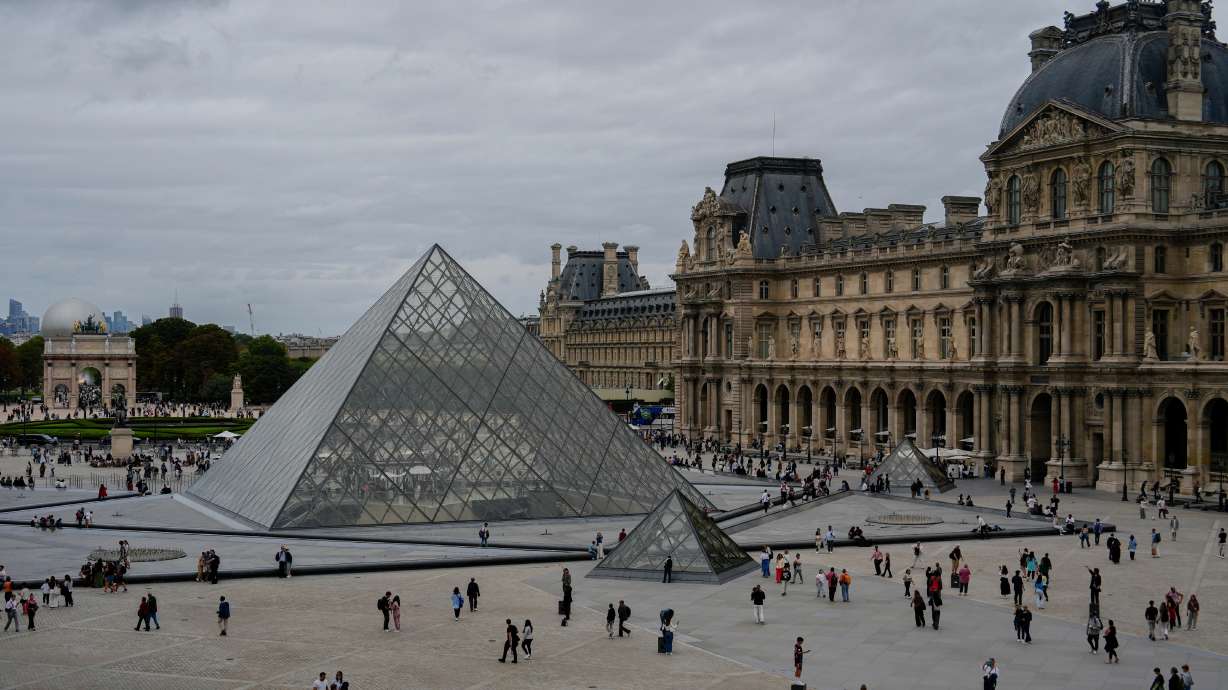 People walk outside the Louvre museum, Aug. 31, in Paris. In a brazen seven-minute strike, thieves used a basket lift to reach the Louvre on Sunday and smashed display cases and fled with jewels of "inestimable value," France's interior minister said.
