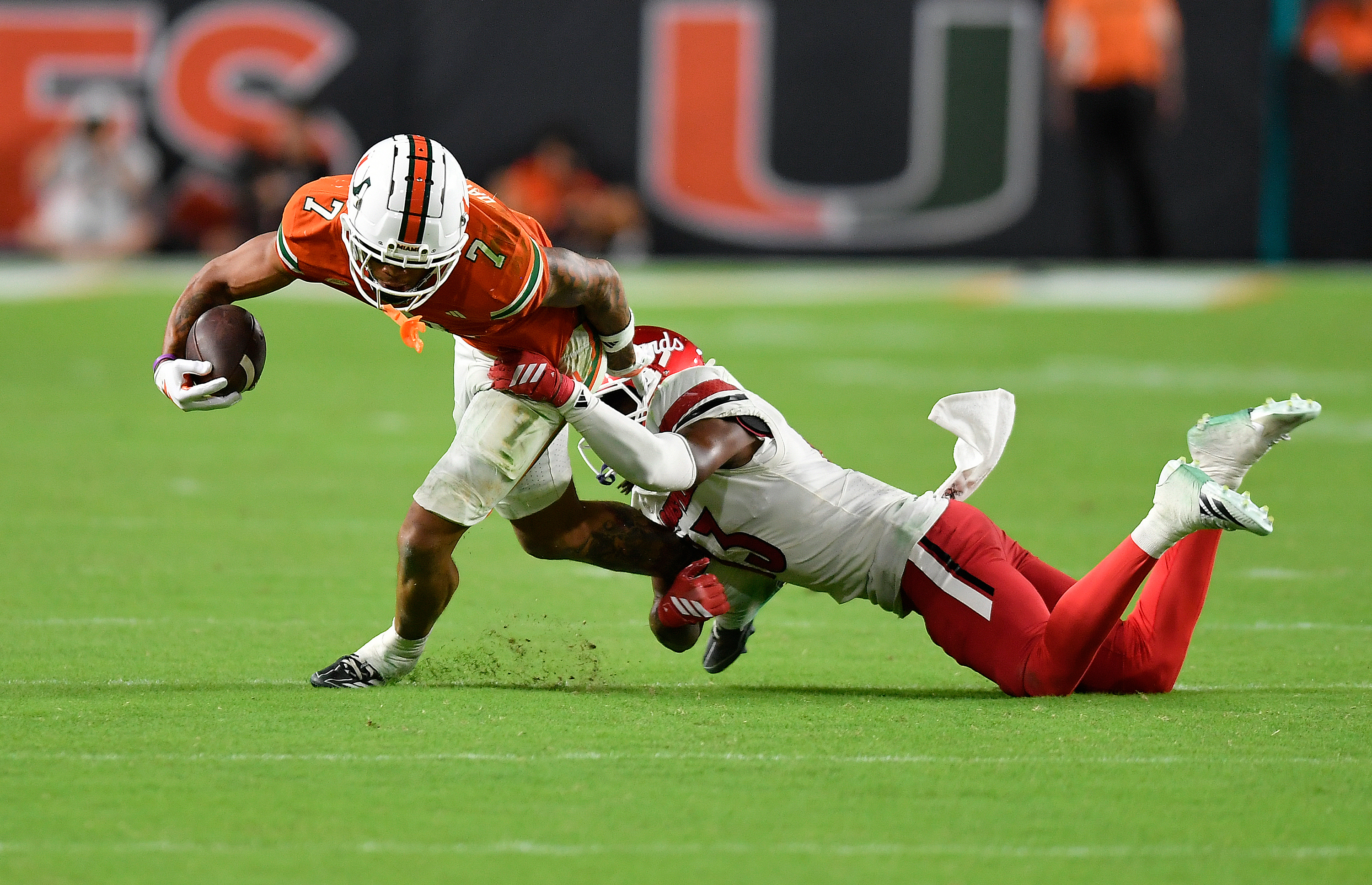 Miami wide receiver CJ Daniels (7) is tackled by Louisville cornerback Justin Agu during the second half of an NCAA college football game, Friday, Oct. 17, 2025, in Miami Gardens, Fla. 