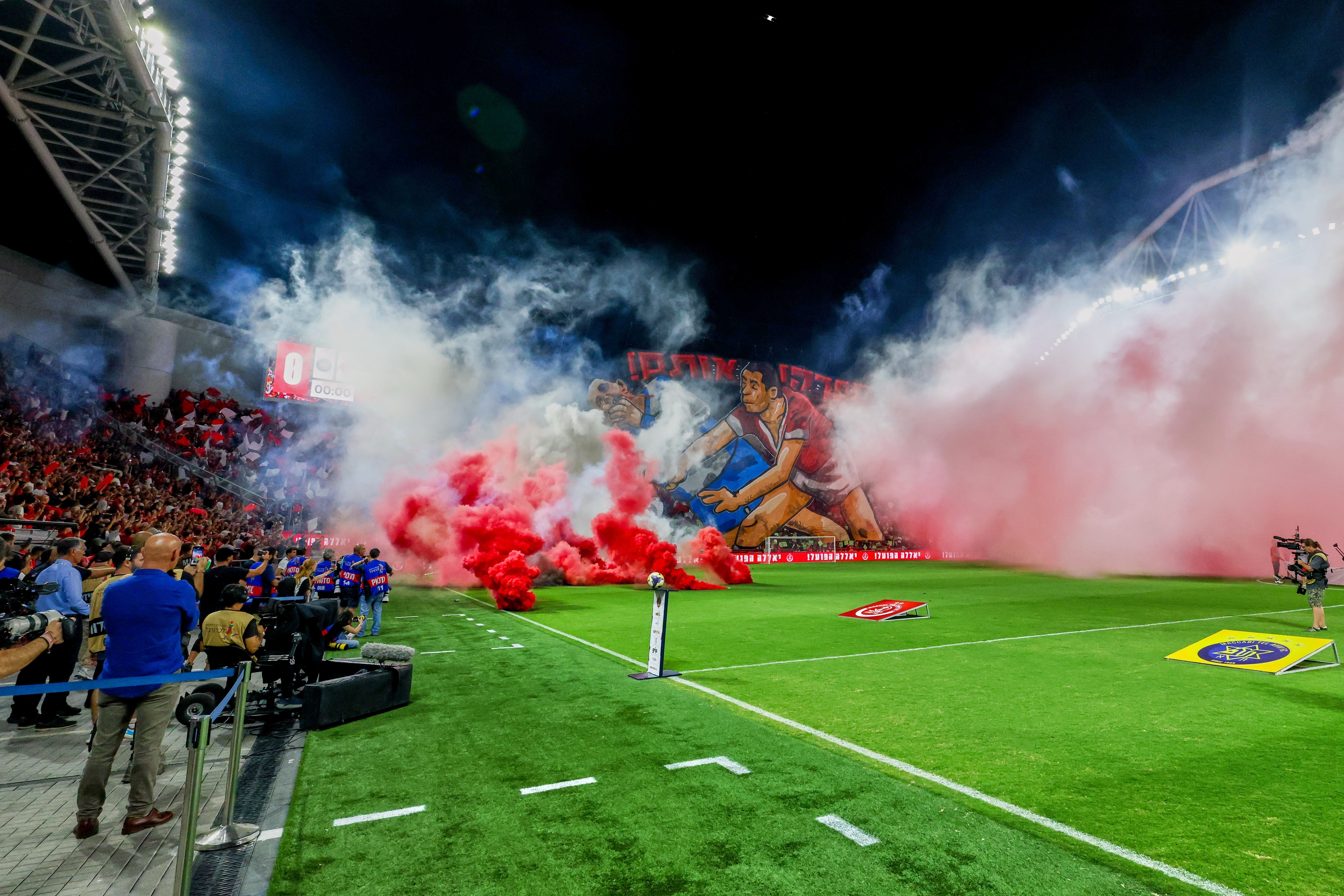 Smoke from flares thrown by fans fills the field before the soccer derby between Maccabi Tel Aviv and Hapoel Tel Aviv was called off Sunday after pregame disturbances led police to deem it unsafe to proceed at Bloomfield Stadium in Tel Aviv, Israel, Sunday, Oct. 19, 2025 . 