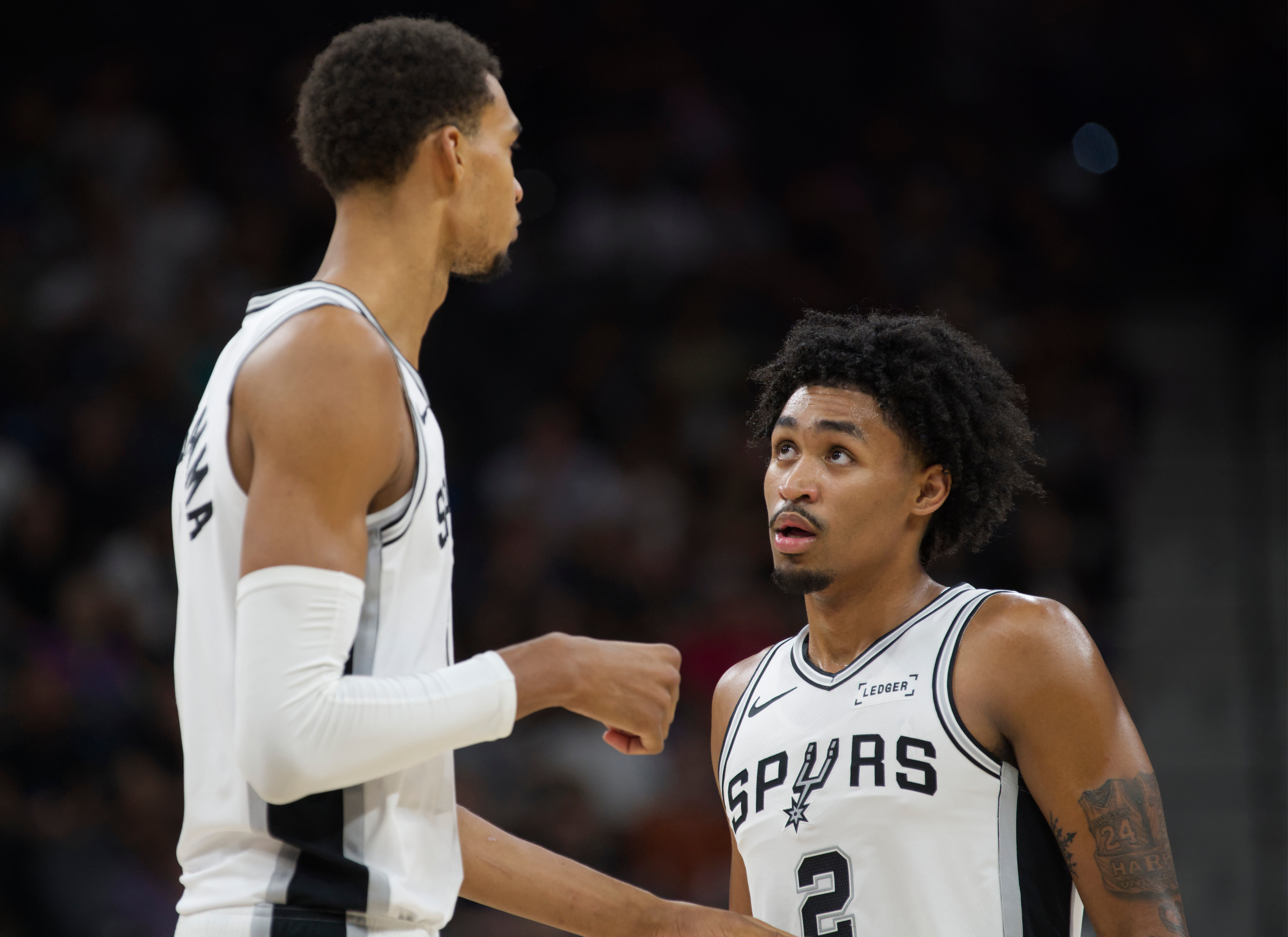 San Antonio Spurs center Victor Wembanyama, left, speaks with teammate Dylan Harper, right, during the first half of a preseason NBA basketball game against the Utah Jazz, Friday, Oct. 10, 2025, in San Antonio. 