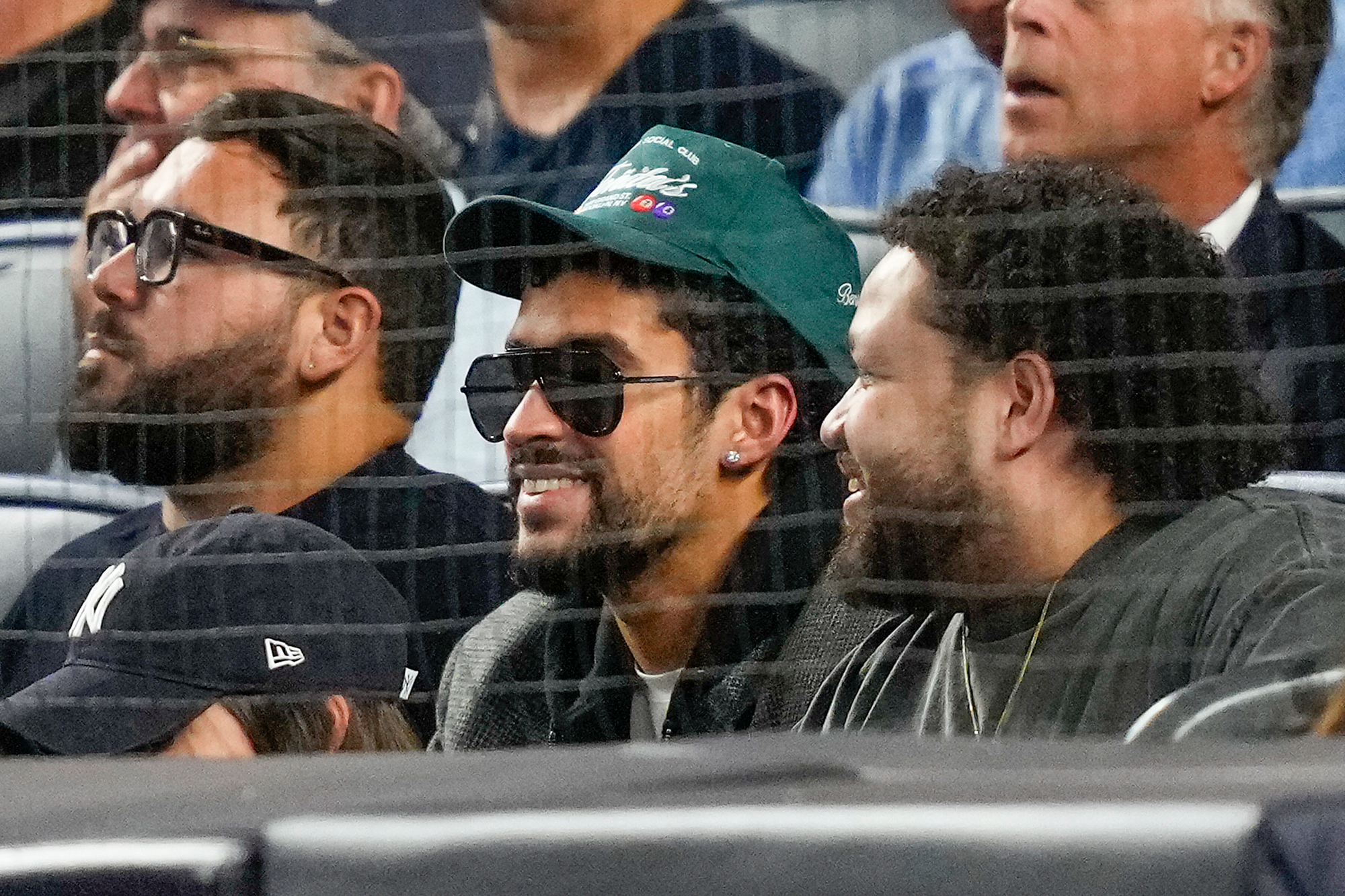 Bad Bunny, center, watches play between the New York Yankees and the Toronto Blue Jays during the second inning of Game 3 of baseball's American League Division Series, Tuesday, Oct. 7, 2025, in New York. 