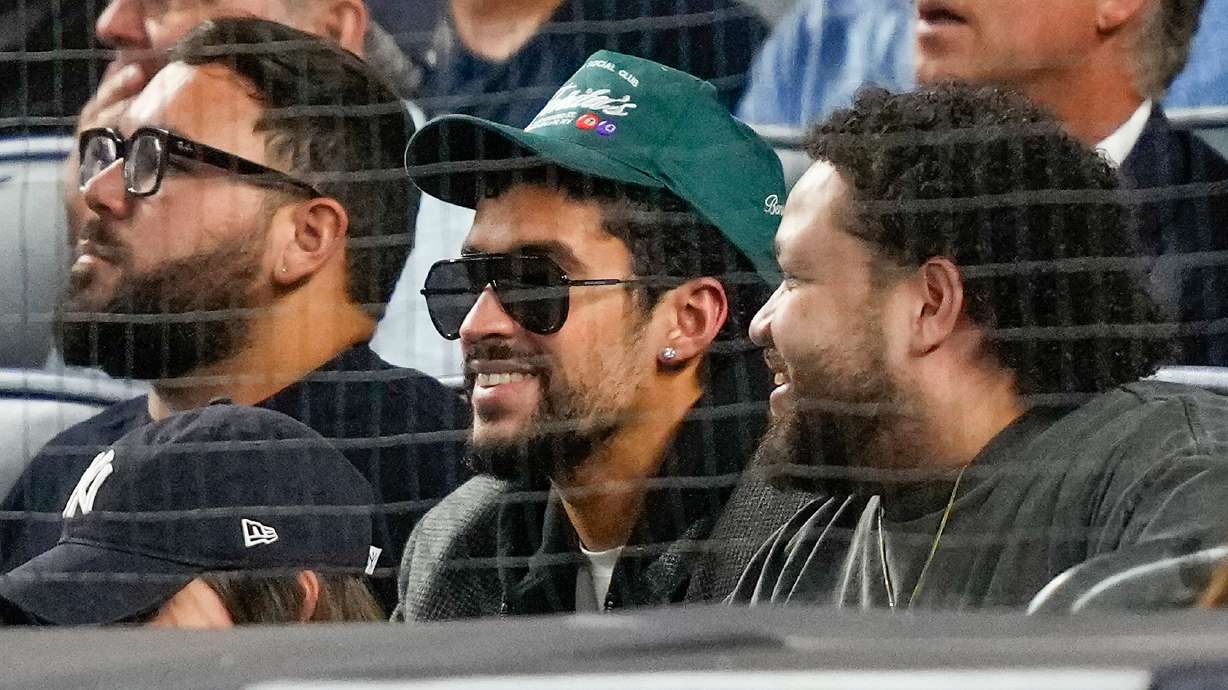 Bad Bunny, center, watches play between the New York Yankees and the Toronto Blue Jays during the second inning of Game 3 of baseball's American League Division Series, Tuesday, Oct. 7, 2025, in New York.