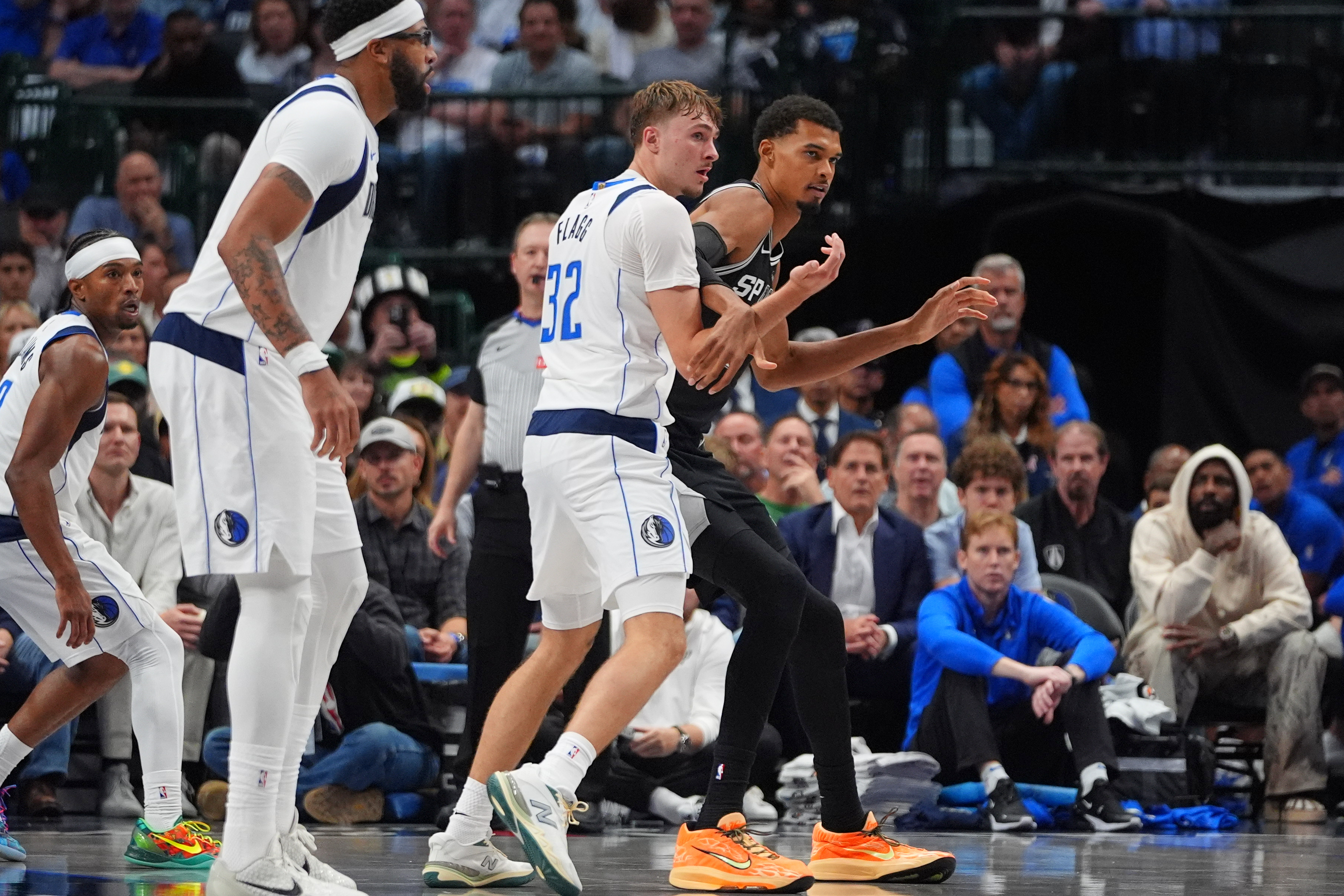 San Antonio Spurs forward Victor Wembanyama, right, is defended by Dallas Mavericks forward Cooper Flagg (32) as forward Anthony Davis, second from left, looks on during the second half of an NBA basketball game in Dallas, Wednesday, Oct. 22, 2025. 