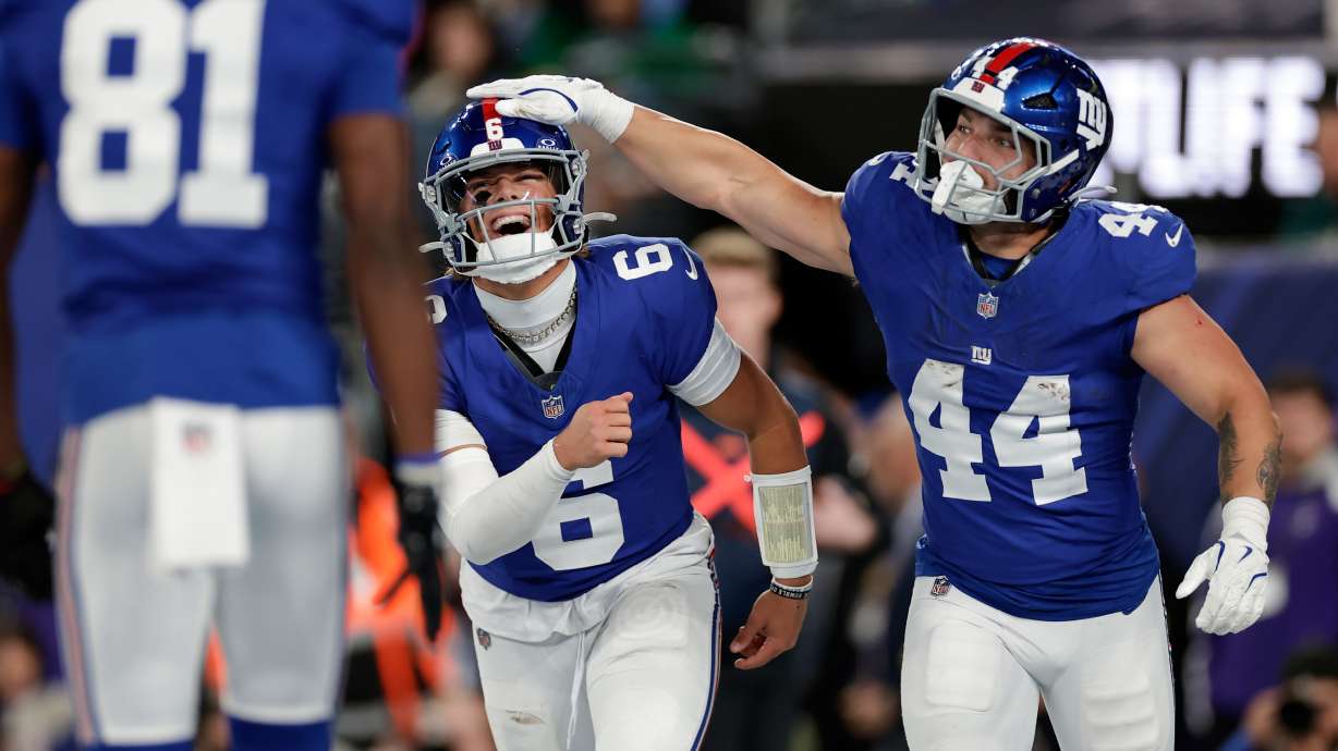New York Giants' Jaxson Dart, center, and Cam Skattebo celebrate after a touchdown during the first half of an NFL football game against the Philadelphia Eagles Thursday, Oct. 9, 2025, in East Rutherford, N.J.