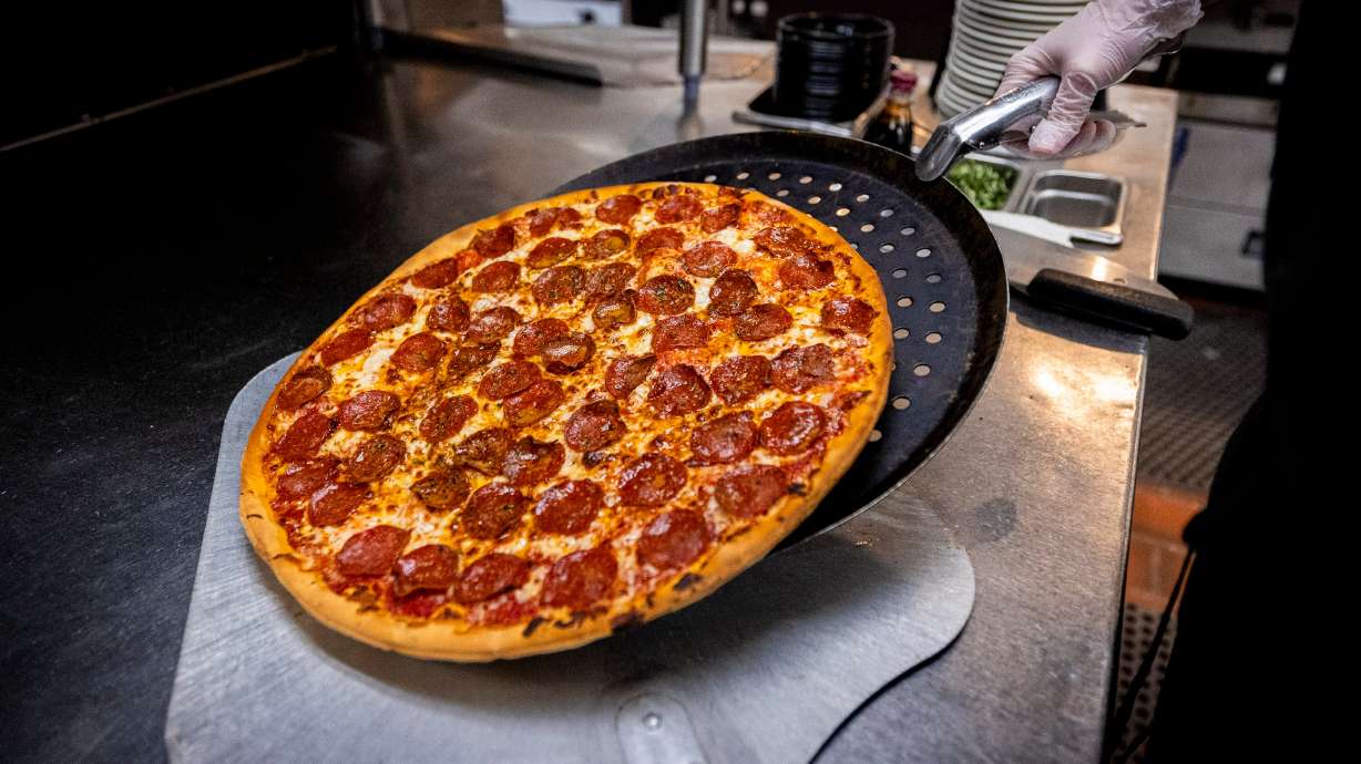 Callie Clegg, kitchen manager at Brick Oven, takes a pizza out of the oven at the restaurant in Provo on Friday.