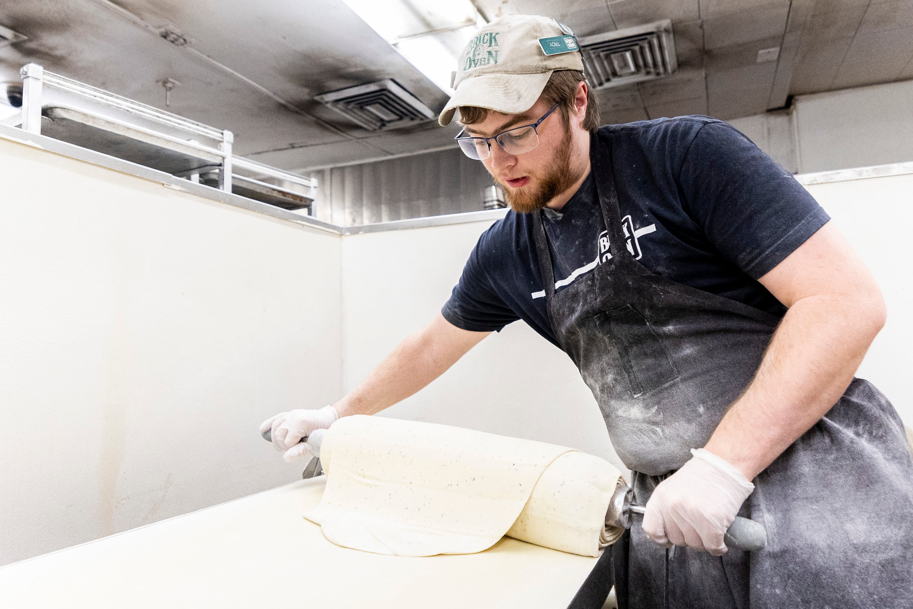 Jacob Roper, dough master at Brick Oven, rolls pizza dough as he prepares it at the restaurant in Provo on Friday.