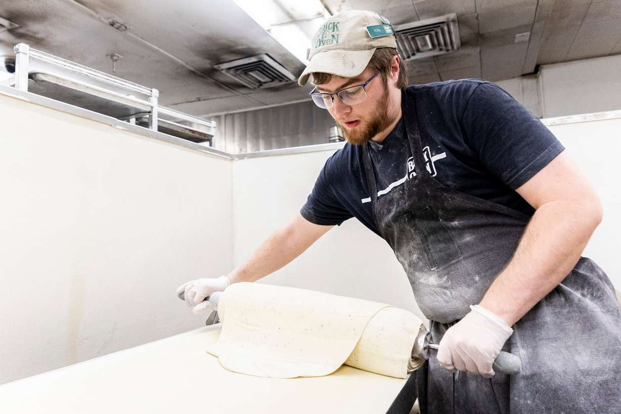Jacob Roper, dough master at Brick Oven, rolls pizza dough as he prepares it at the restaurant in Provo on Friday.