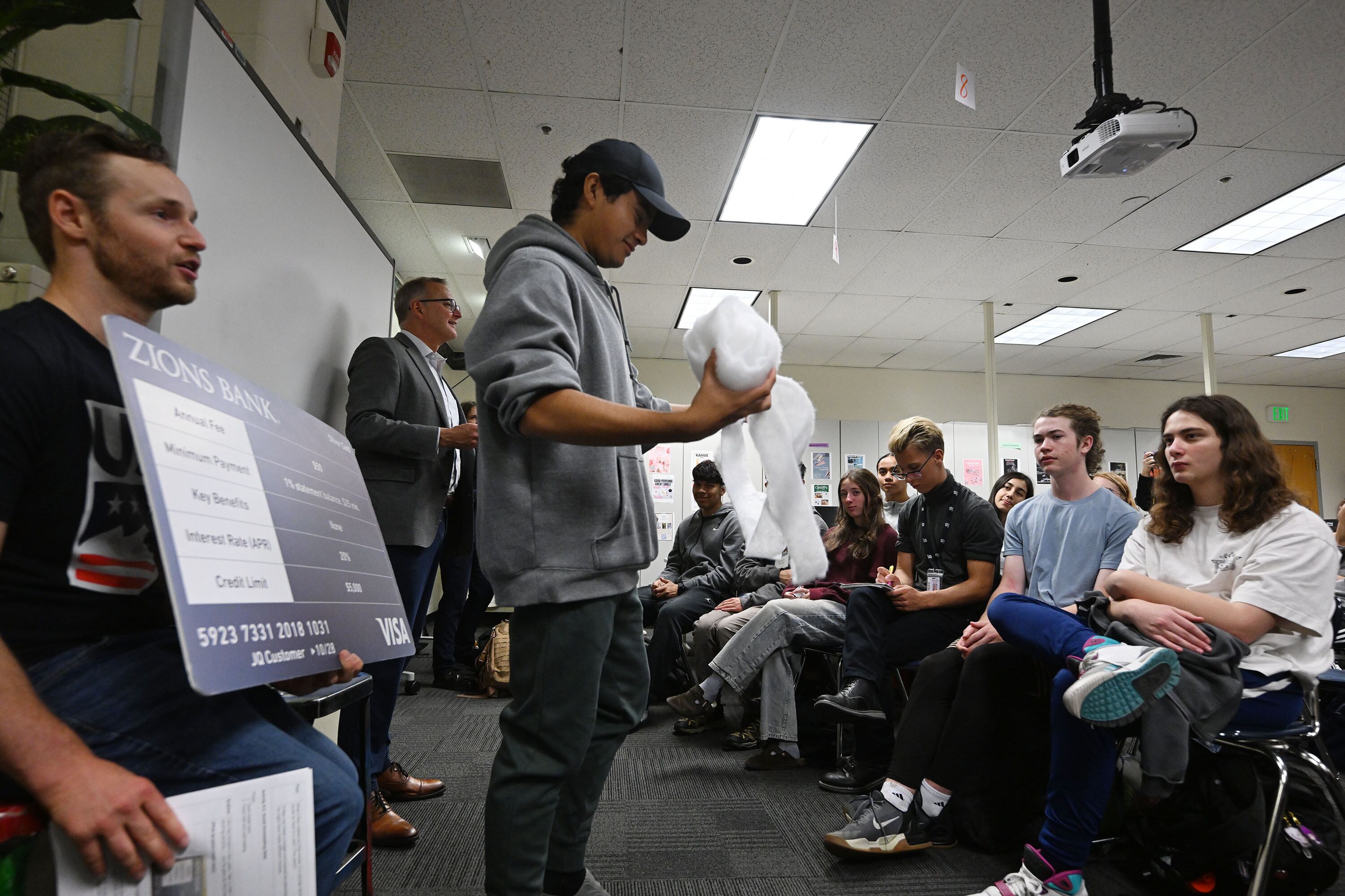 West High School student Oscar Cubias Diaz rolls up a ball of cotton, symbolizing a rolling ball of snow getting larger and larger, as Paul Burdiss, Zions Bank president and CEO, joins with Olympic athletes Andrew Haraghey and Landon Wendler in discussing the practice of financial discipline being a key to avoiding snowballing debt in life on Friday.