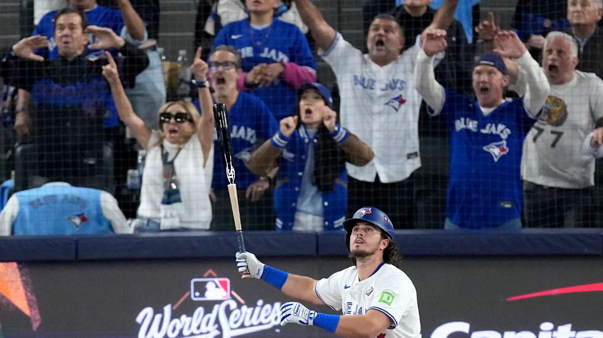 Toronto Blue Jays' Addison Barger watches his grand slam home run take flight as Los Angeles Dodgers' pitcher Anthony Banda, left, looks away uring the sixth inning in Game 1 of baseball's World Series, Friday, Oct. 24, 2025, in Toronto.