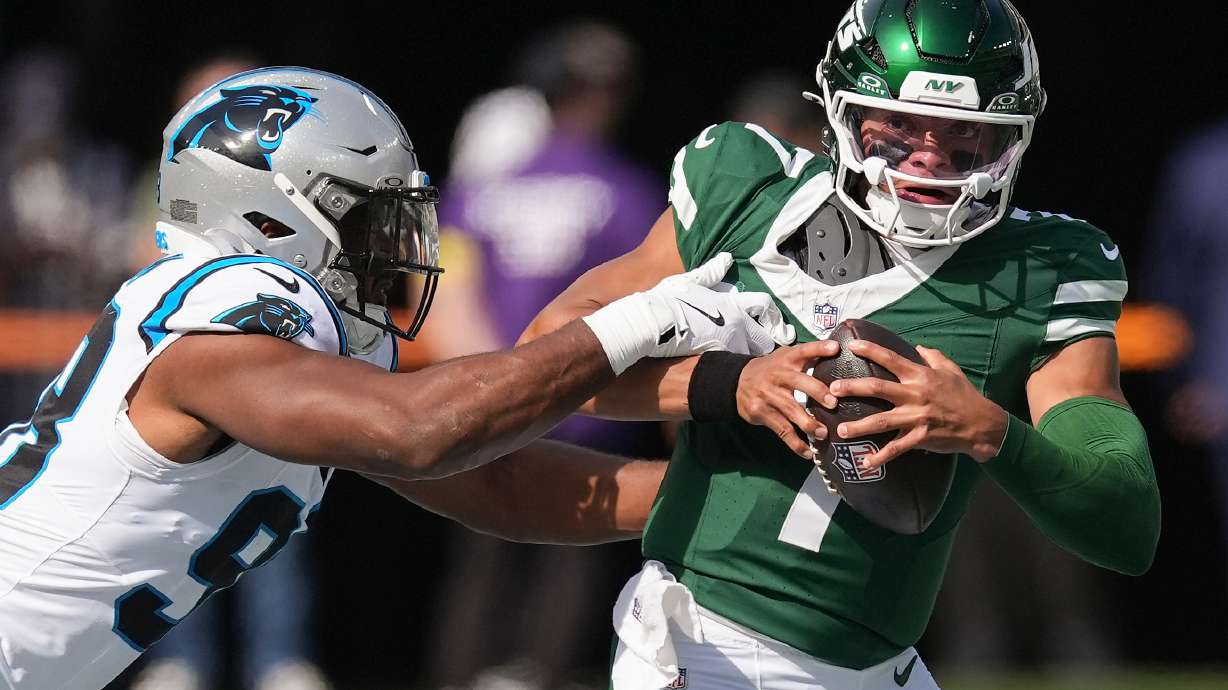 New York Jets quarterback Justin Fields (7) tries to avoid a tackle by Carolina Panthers linebacker D.J. Wonnum (98) during the first quarter of an NFL football game, Sunday, Oct. 19, 2025, in East Rutherford, N.J.