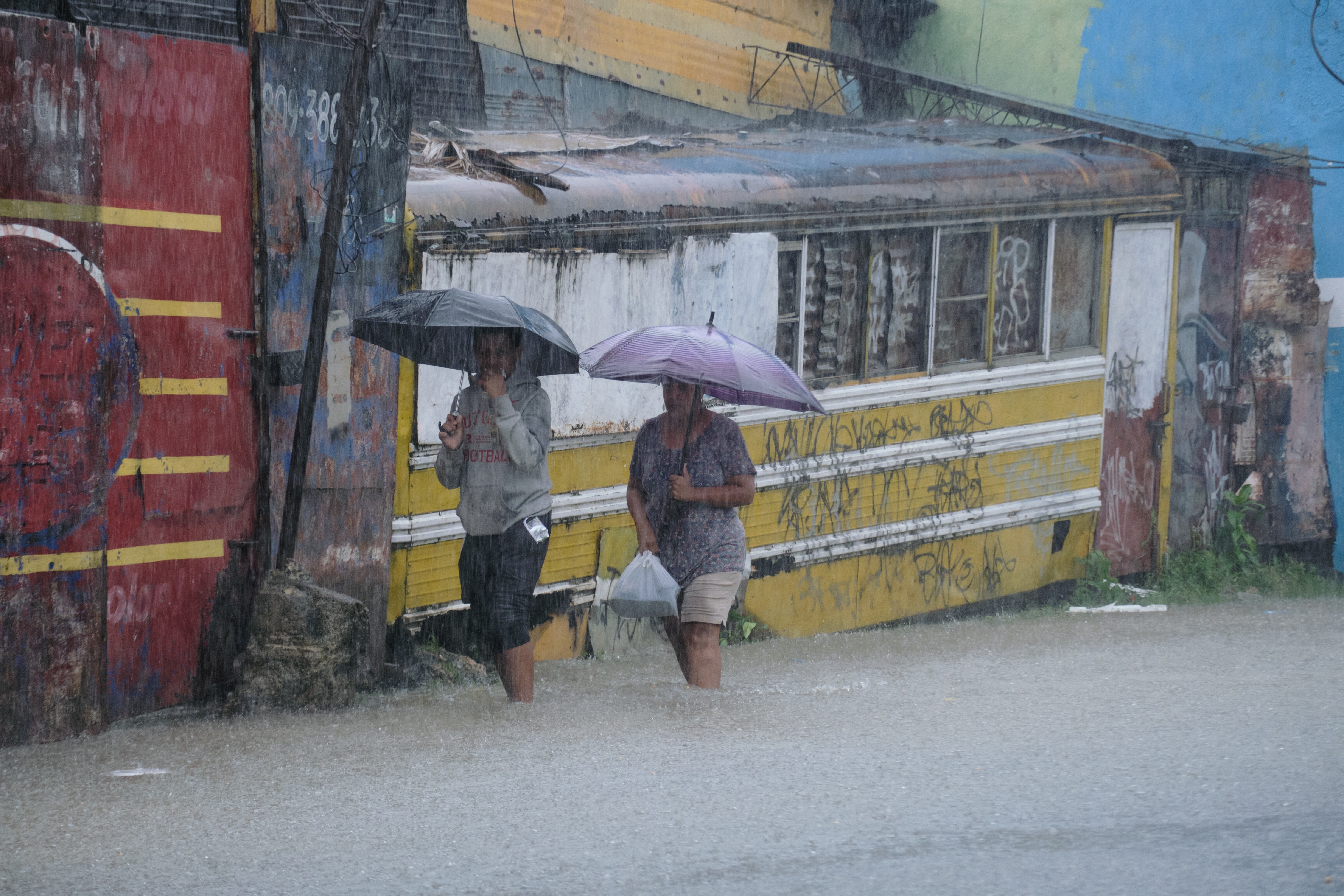 People wade through a street flooded by rains caused by then-Tropical Storm Melissa in Santo Domingo, Dominican Republic, Friday. Melissa reached hurricane strength on Saturday and is approaching major hurricane status.