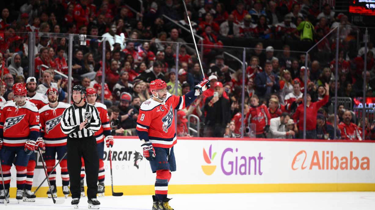 Washington Capitals left wing Alex Ovechkin (8) raises his stick to the crowd after he was recognized for playing in his 1,500th NHL hockey game during a break in the action in the first period against the Ottawa Senators, Saturday, Oct. 25, 2025, in Washington.