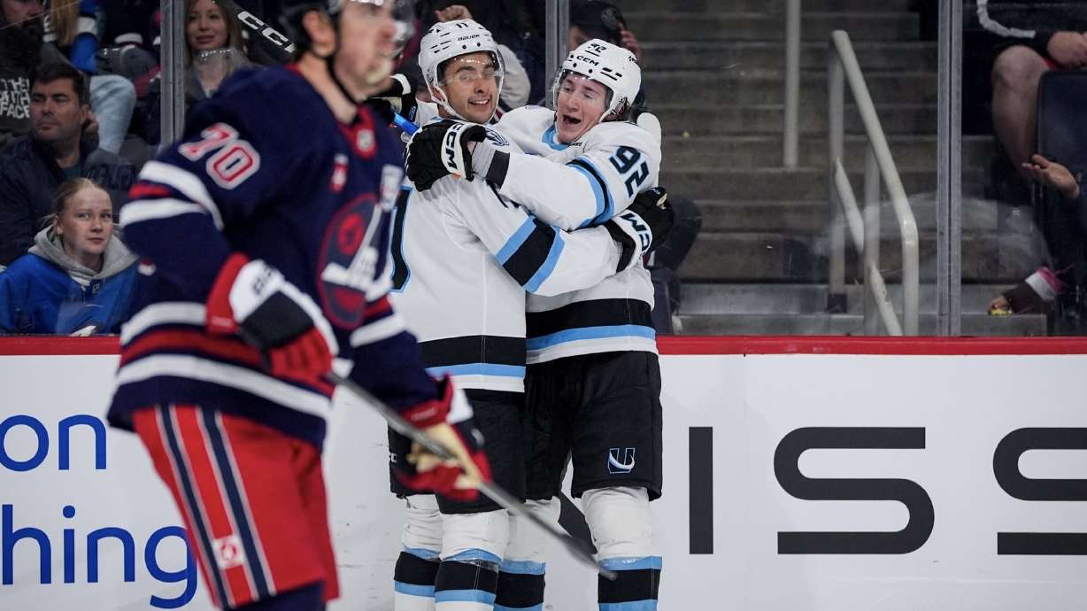 Dylan Guenther, middle, and Logan Cooley, right, celebrate the game-winner against Winnipeg.