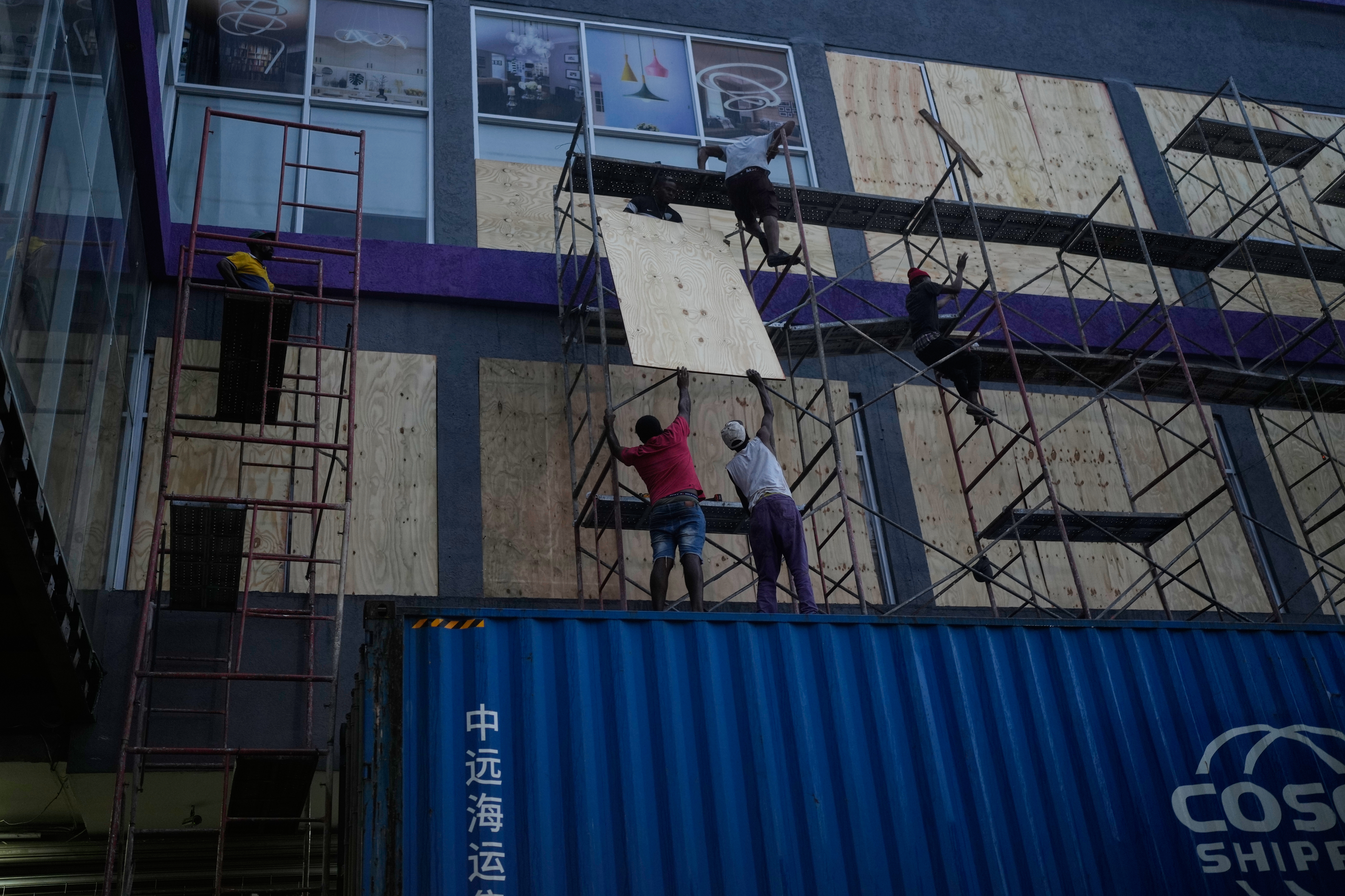 Workers board up shop windows ahead of Hurricane Melissa's forecast arrival in Kingston, Jamaica, Sunday.