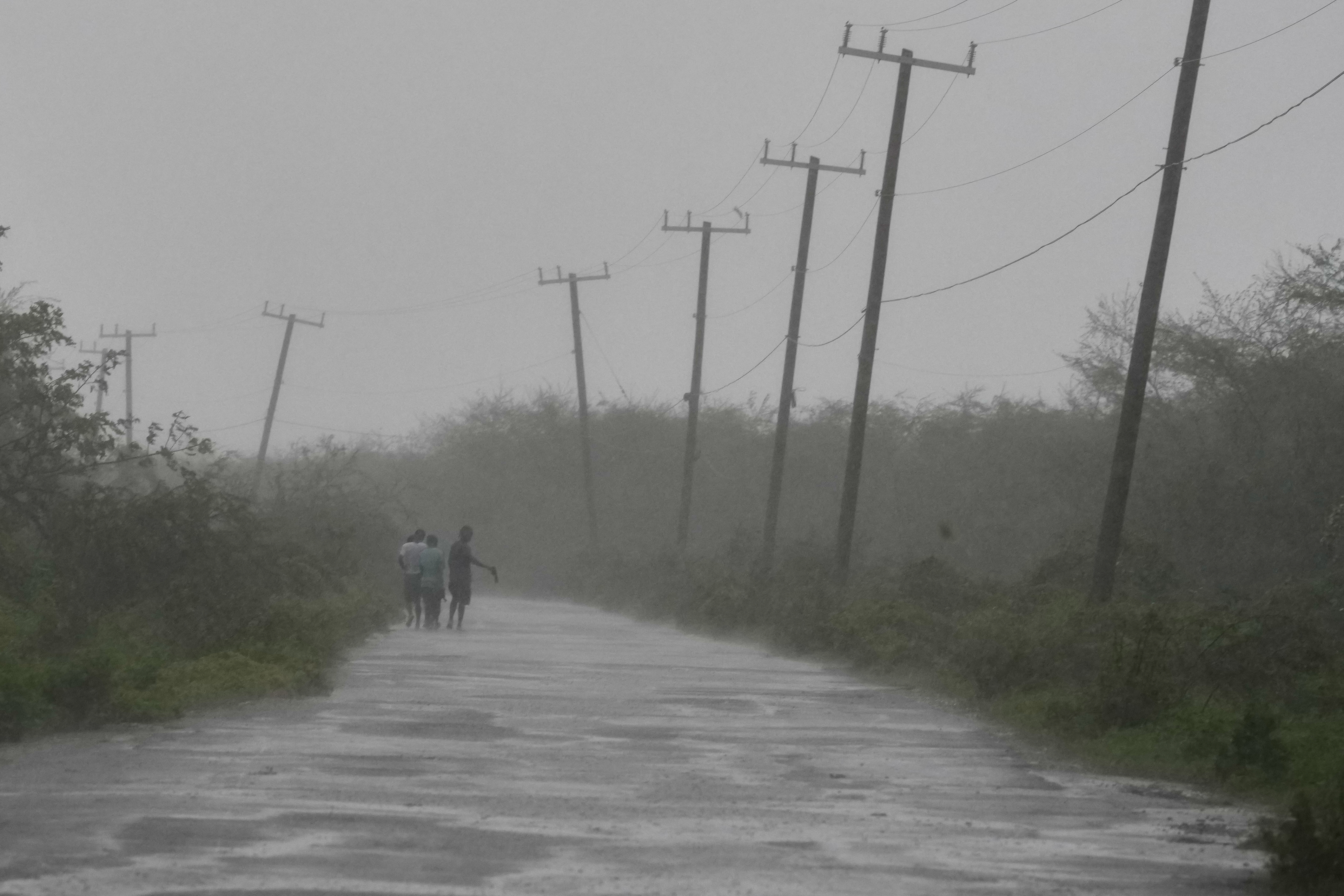 People walk along a road during the passing of Hurricane Melissa in Rocky Point, Jamaica, Tuesday. The storm made landfall with sustained winds of 185 mph, tying a record for the strongest winds on landfall in Atlantic hurricane history.
