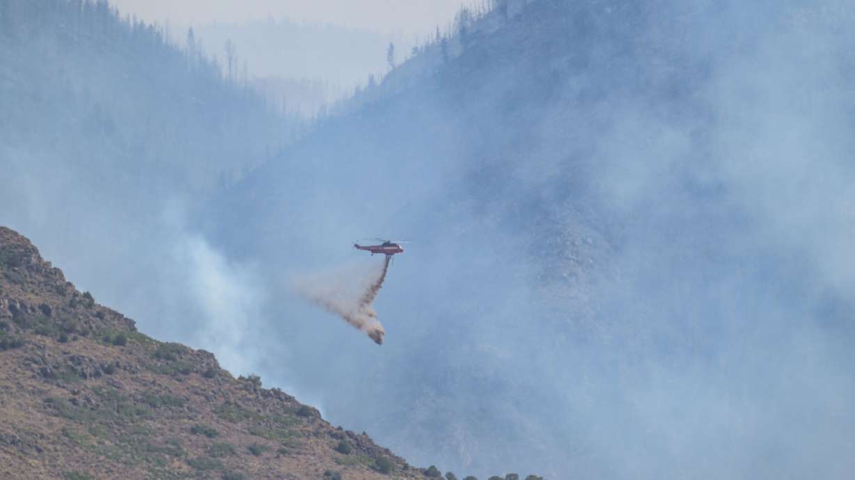 A helicopter makes a drop on the Monroe Canyon Fire on Aug. 5, 2025. The fire cost close to $100 million, accounting for most of the estimated wildfire suppression costs last year, Utah officials said on Wednesday.