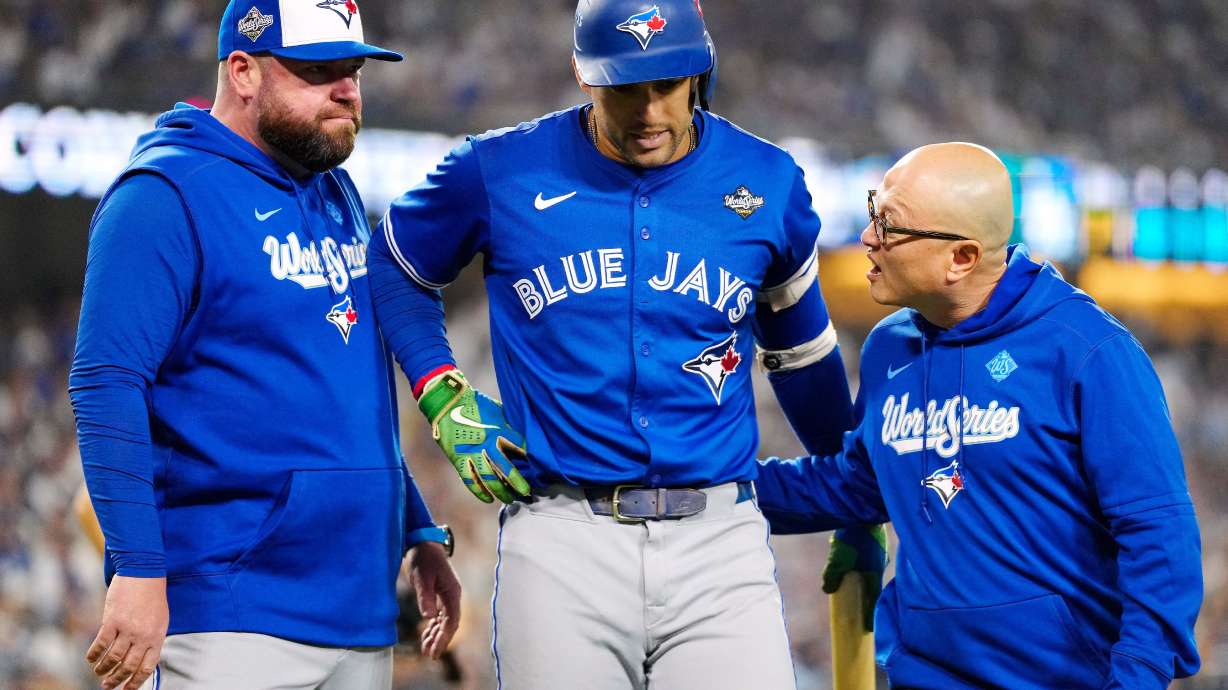 Toronto Blue Jays' George Springer, center, walks off the field as he leaves with an injury with manager John Schneider, left, and first assistant athletic trainer Voon Chong, right, during the seventh inning in Game 3 of baseball's World Series against the Los Angeles Dodgers in Los Angeles, Monday, Oct. 27, 2025.